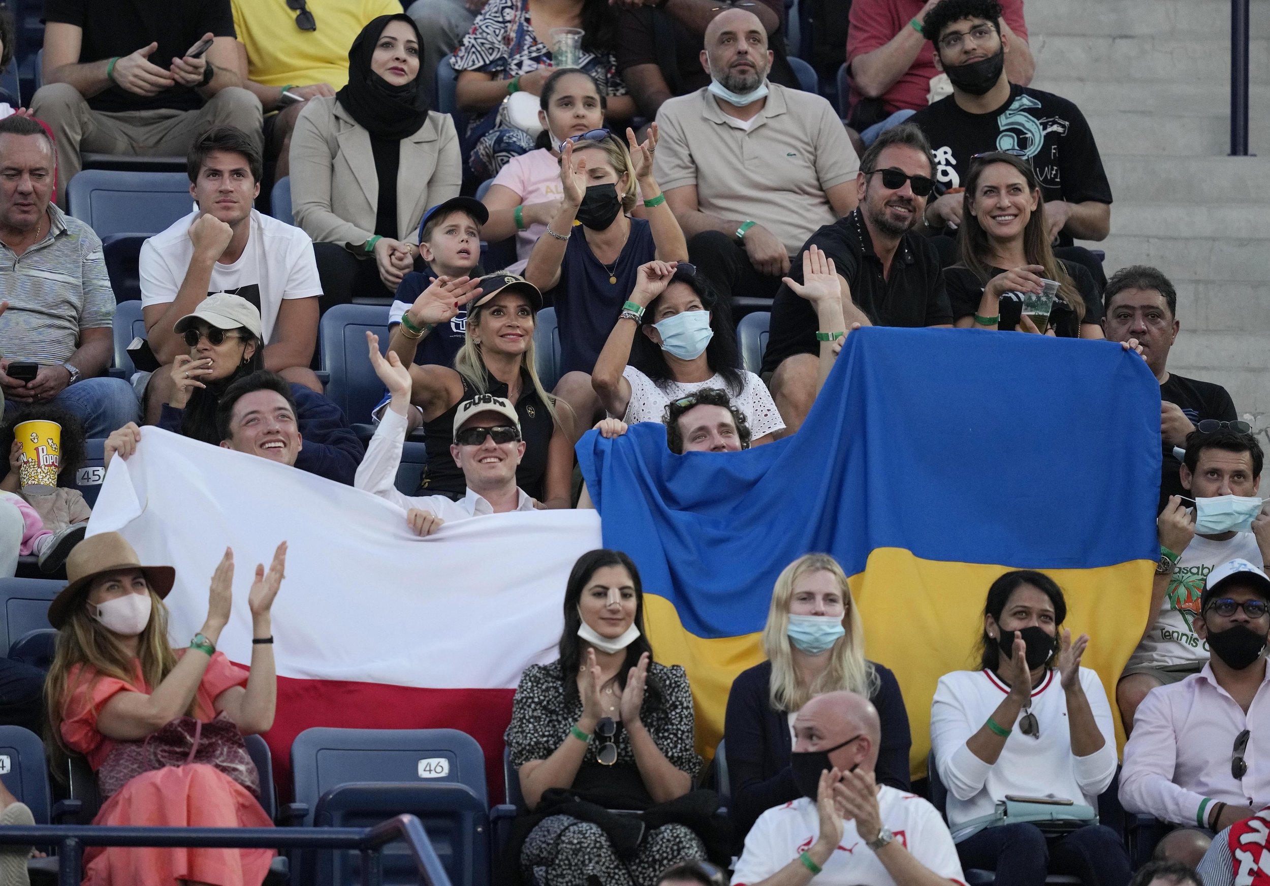  Fans hold a Ukraine national flag next to a Polish flag during a semifinal tennis match between Russia's Andrey Rublev and Poland's Hubert Hurkacz at the Dubai Duty Free Tennis Championship in Dubai, United Arab Emirates, Feb. 25, 2022. (AP Photo/Ka