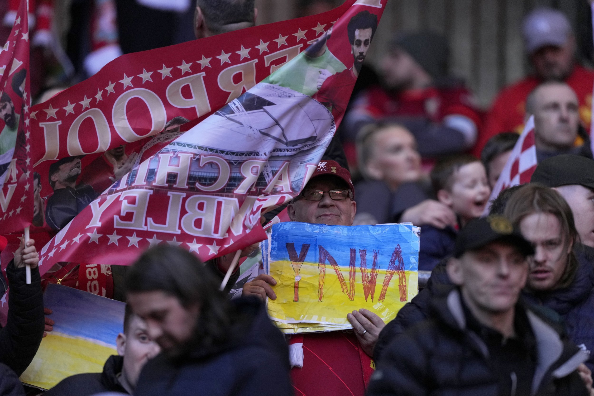  A Liverpool fan holds a sign in the Ukrainian colors with the initials of "You'll Never Walk Alone", the Liverpool anthem sung by the fans every game, during the English League Cup final soccer match between Chelsea and Liverpool at Wembley stadium 