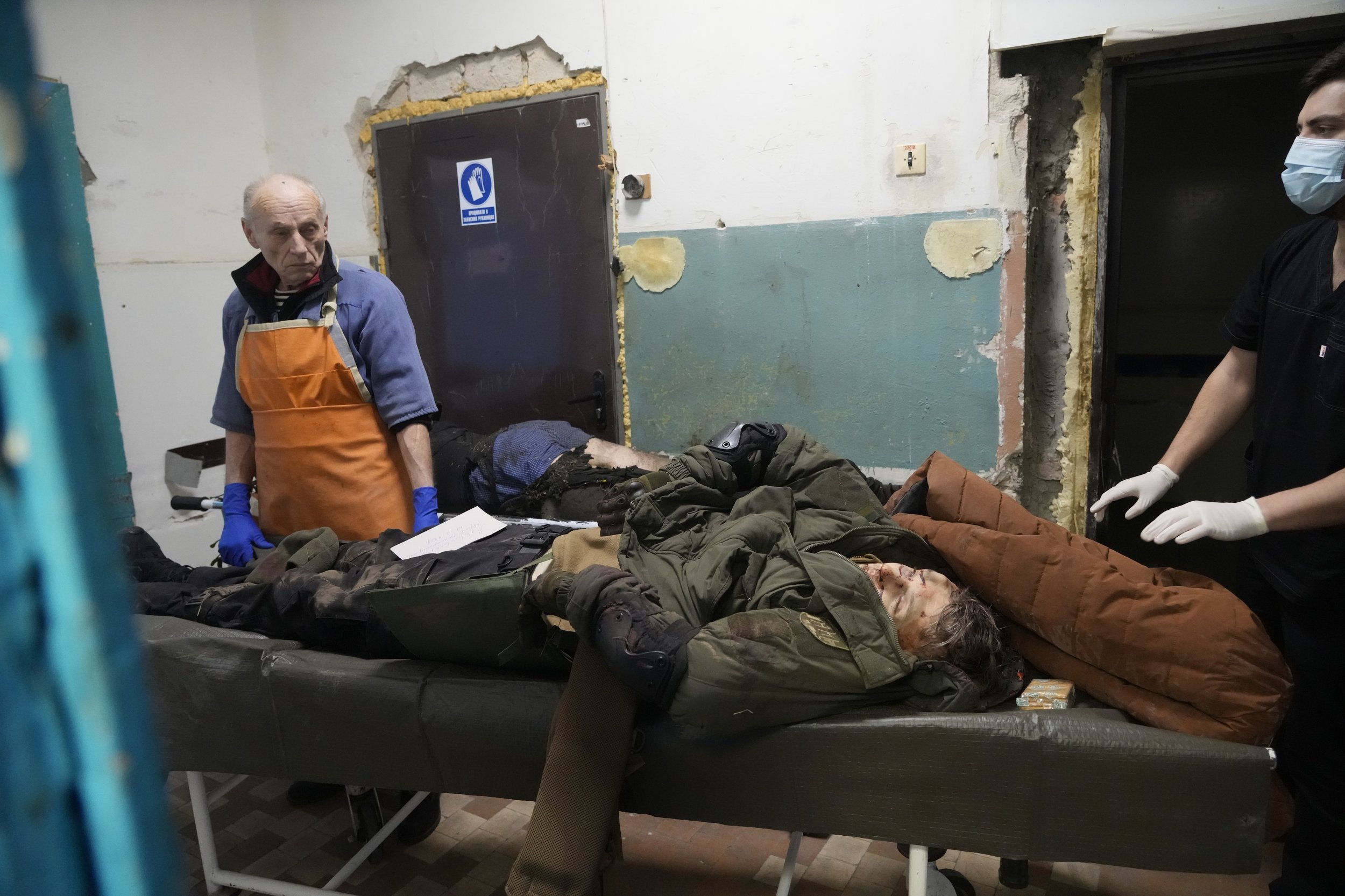  EDS NOTE: GRAPHIC CONTENT - Morgue workers look at the body of a killed volunteer of Ukraine's Territorial Defense Forces at a hospital in Brovary, outside Kyiv, Ukraine, Tuesday, March 1, 2022. (AP Photo/Efrem Lukatsky) 