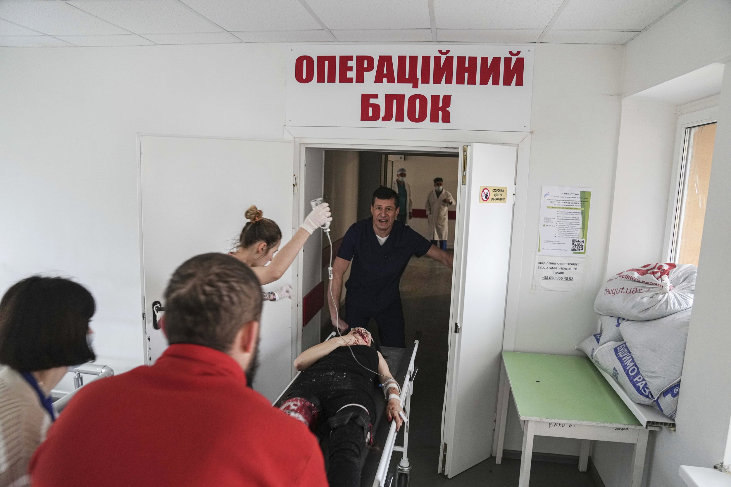  Oleksandr Konovalov, an ambulance paramedic, center, pushes a stretcher with a woman injured by shelling in a residential area at a maternity hospital converted into a medical ward in Mariupol, Ukraine, Tuesday, March 1, 2022. (AP Photo/Evgeniy Malo
