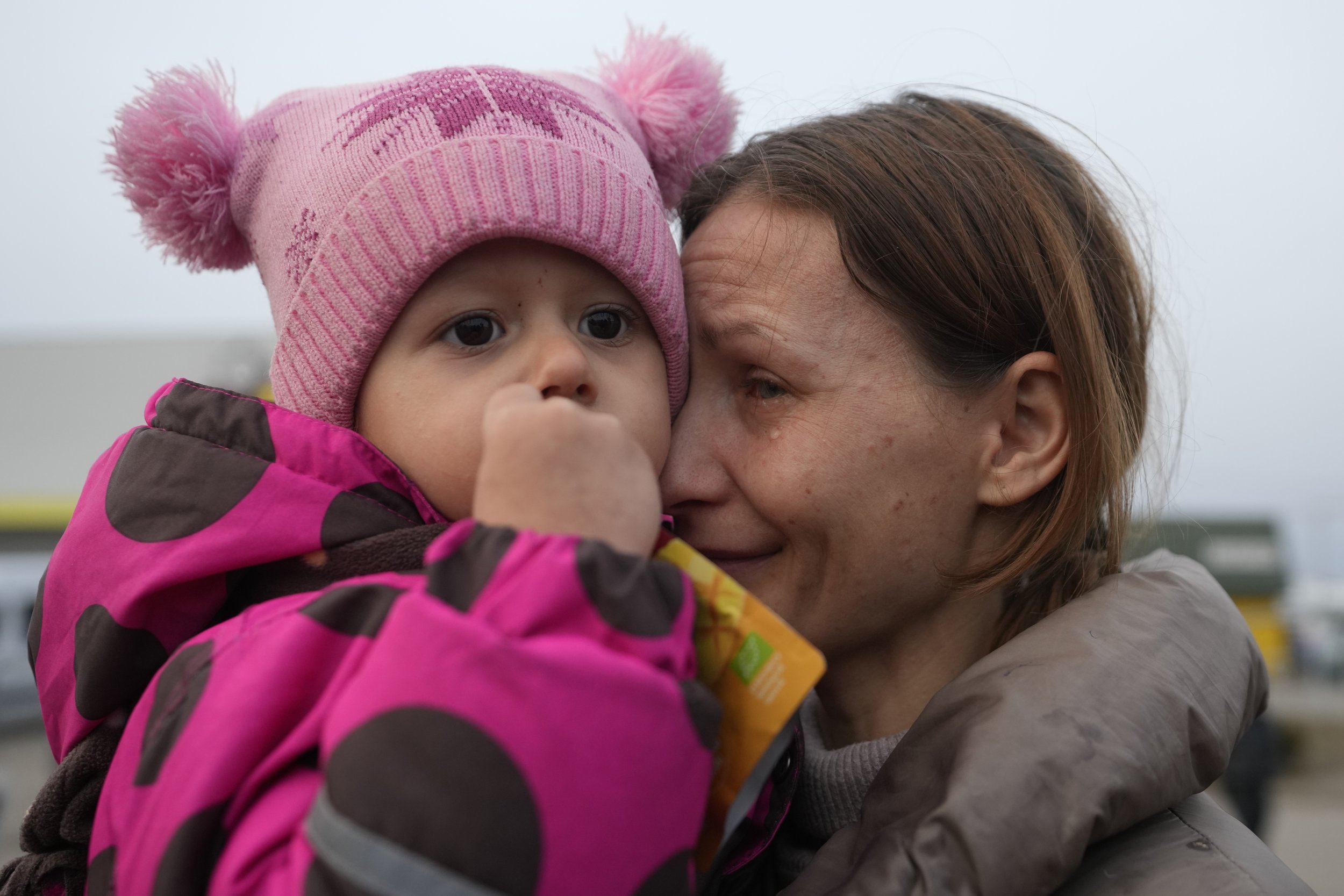  A women with a child who fled from the war in Ukraine reacts as they reunite with their family after crossing the border in Medyka, Poland, Tuesday, March 1, 2022. (AP Photo/Markus Schreiber) 