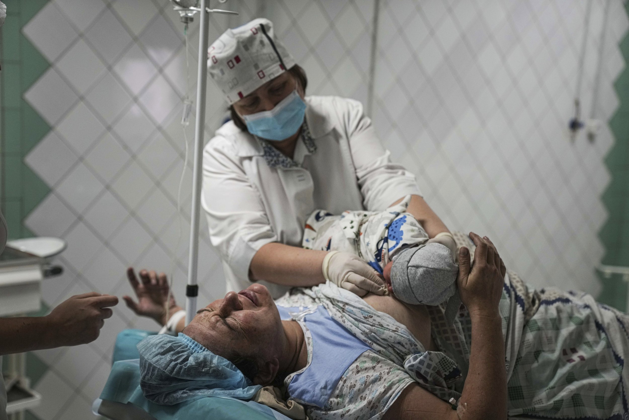  A nurse shows a newborn baby to a woman who gave birth at a maternity hospital converted into a medical ward in Mariupol, Ukraine, Tuesday, March 1, 2022. (AP Photo/Evgeniy Maloletka) 
