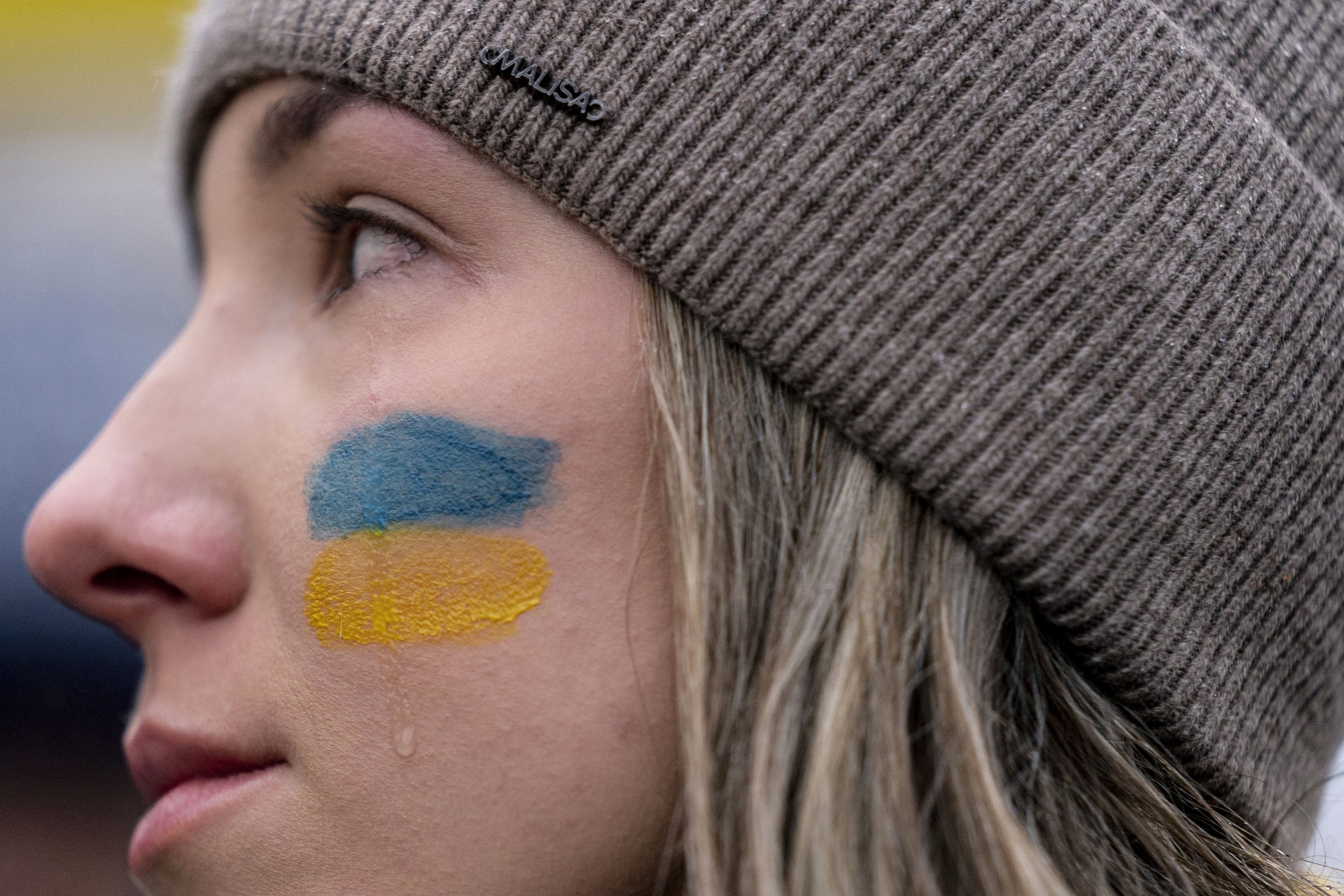  A tear rolls down through the colors of the Ukrainian flag on the cheek of Ukranian Oleksandra Yashan of Arlington, Va., as she becomes emotional during a vigil to protest the Russian invasion of Ukraine in Lafayette Park in front of the White House
