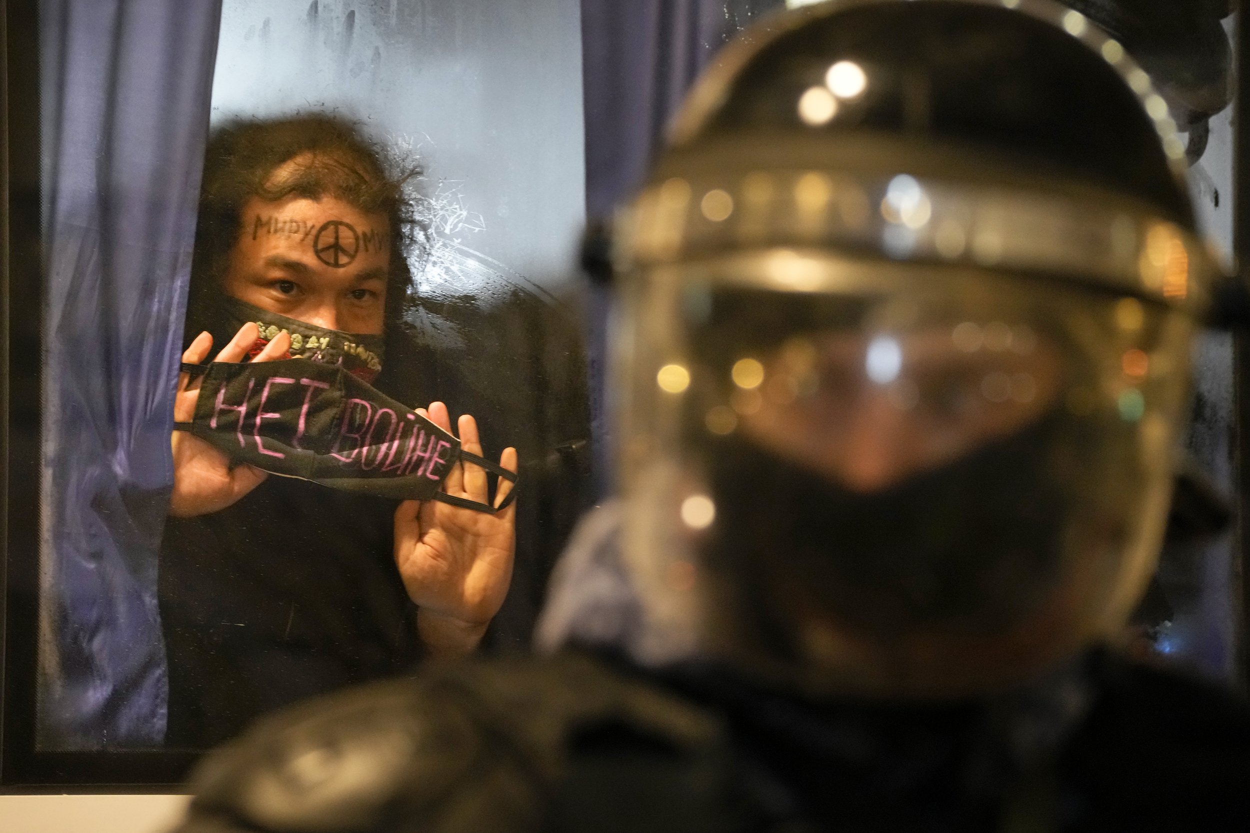  A detained demonstrator shows a sign 'No War!' from a police bus in St. Petersburg, Russia, Thursday, Feb. 24, 2022. Hundreds of people gathered in Moscow and St. Petersburg on Thursday, protesting against Russia's attack on Ukraine. (AP Photo/Dmitr