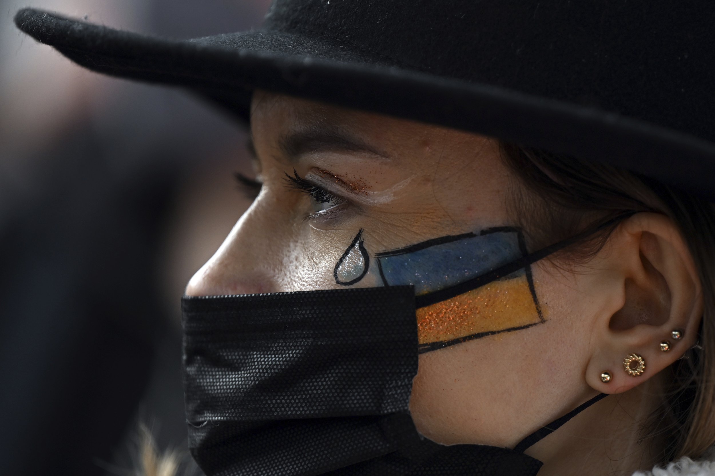  A woman with a Ukrainian flag and a tear painted on her face, takes part in a protest following Russian attack on Ukraine, in Cologne, Germany, Thursday, Feb. 24, 2022. (Federico Gambarini/dpa via AP) 