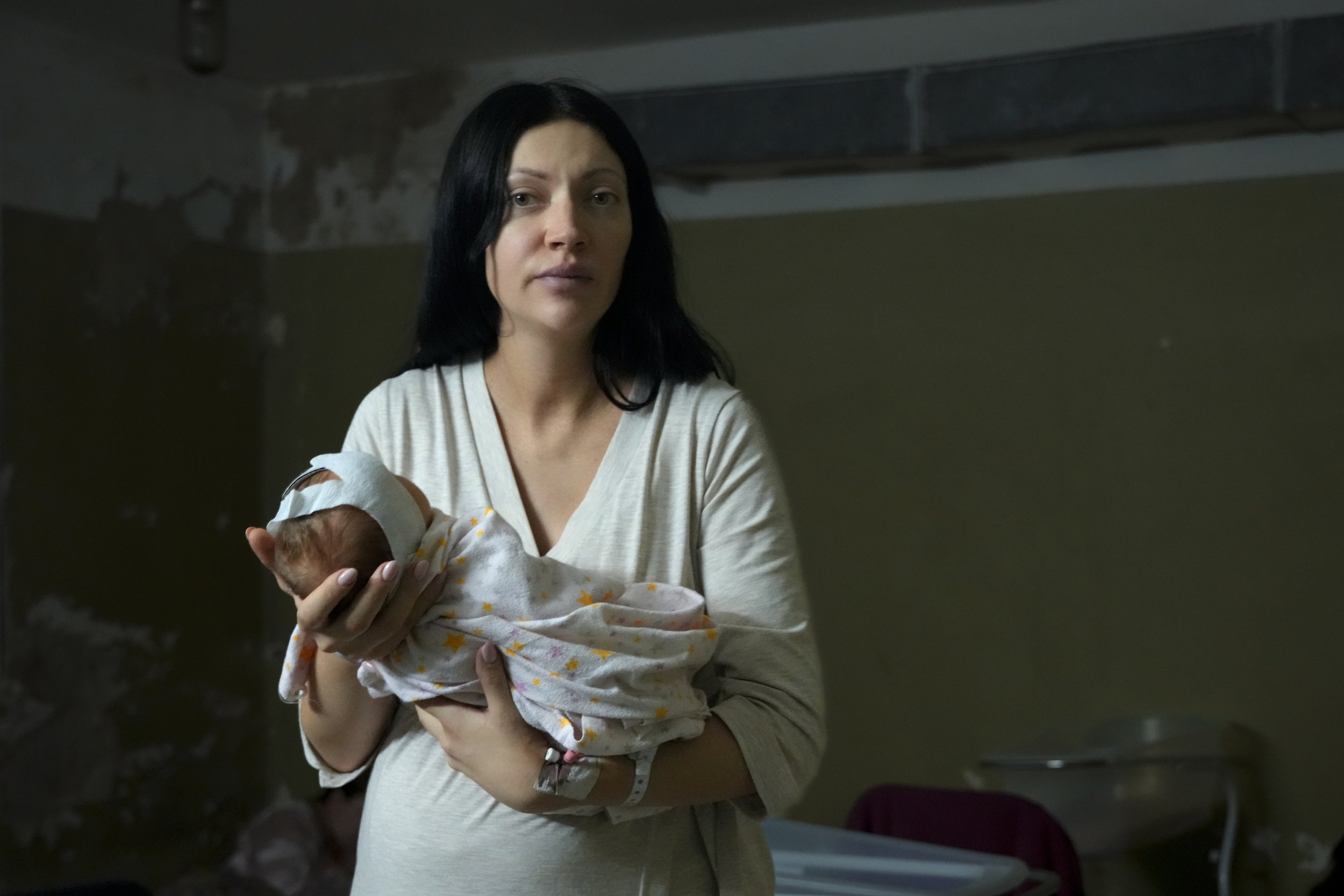 A woman, who did not want to be identified, poses for a photograph as she holds her newborn girl in the basement of a maternity hospital converted into a medical ward and used as a bomb shelter during air raid alerts, in Kyiv, Ukraine, Wednesday, Ma