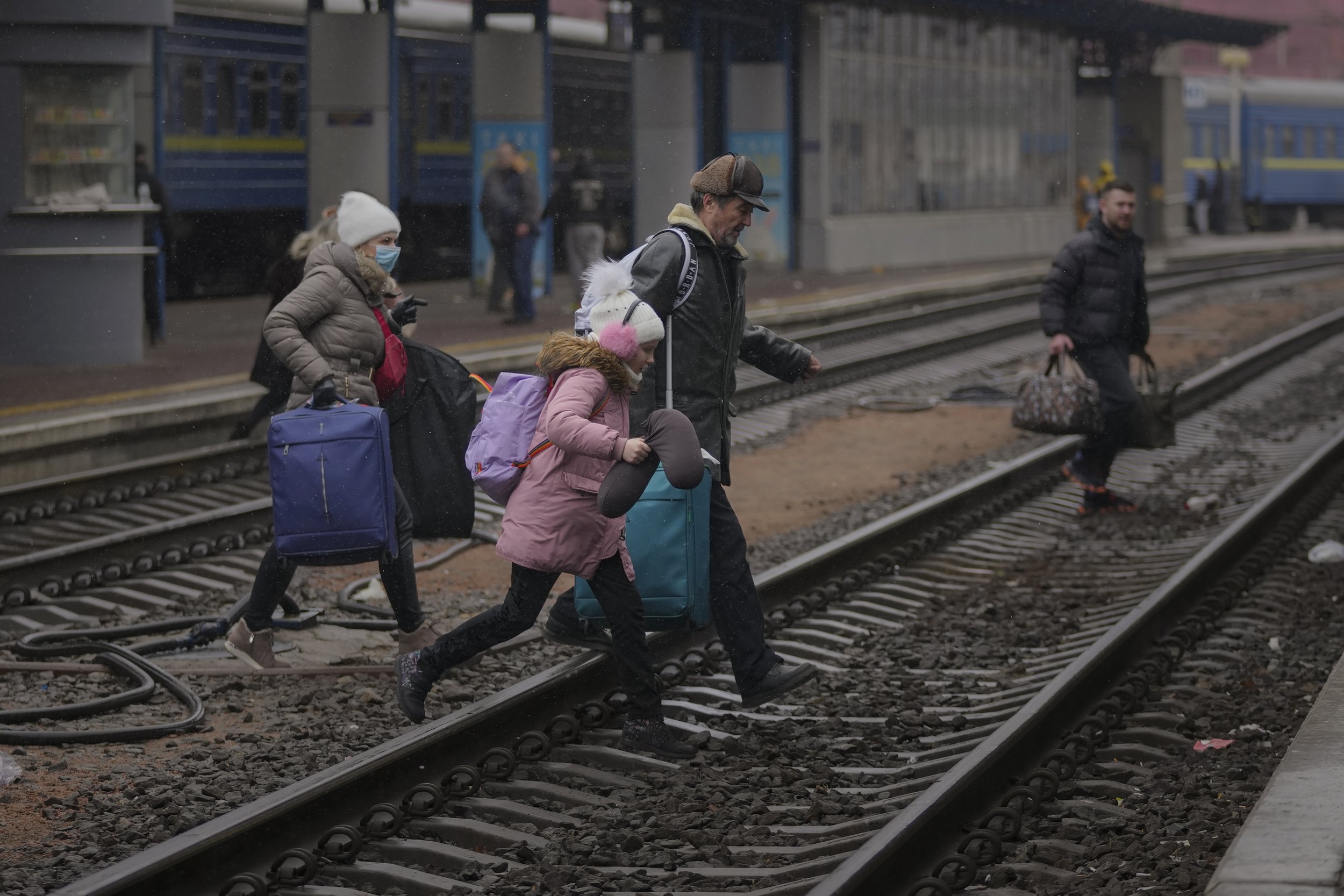  A family runs over the tracks trying to board a Lviv bound train, in Kyiv, Ukraine, Thursday, March 3, 2022. (AP Photo/Vadim Ghirda) 