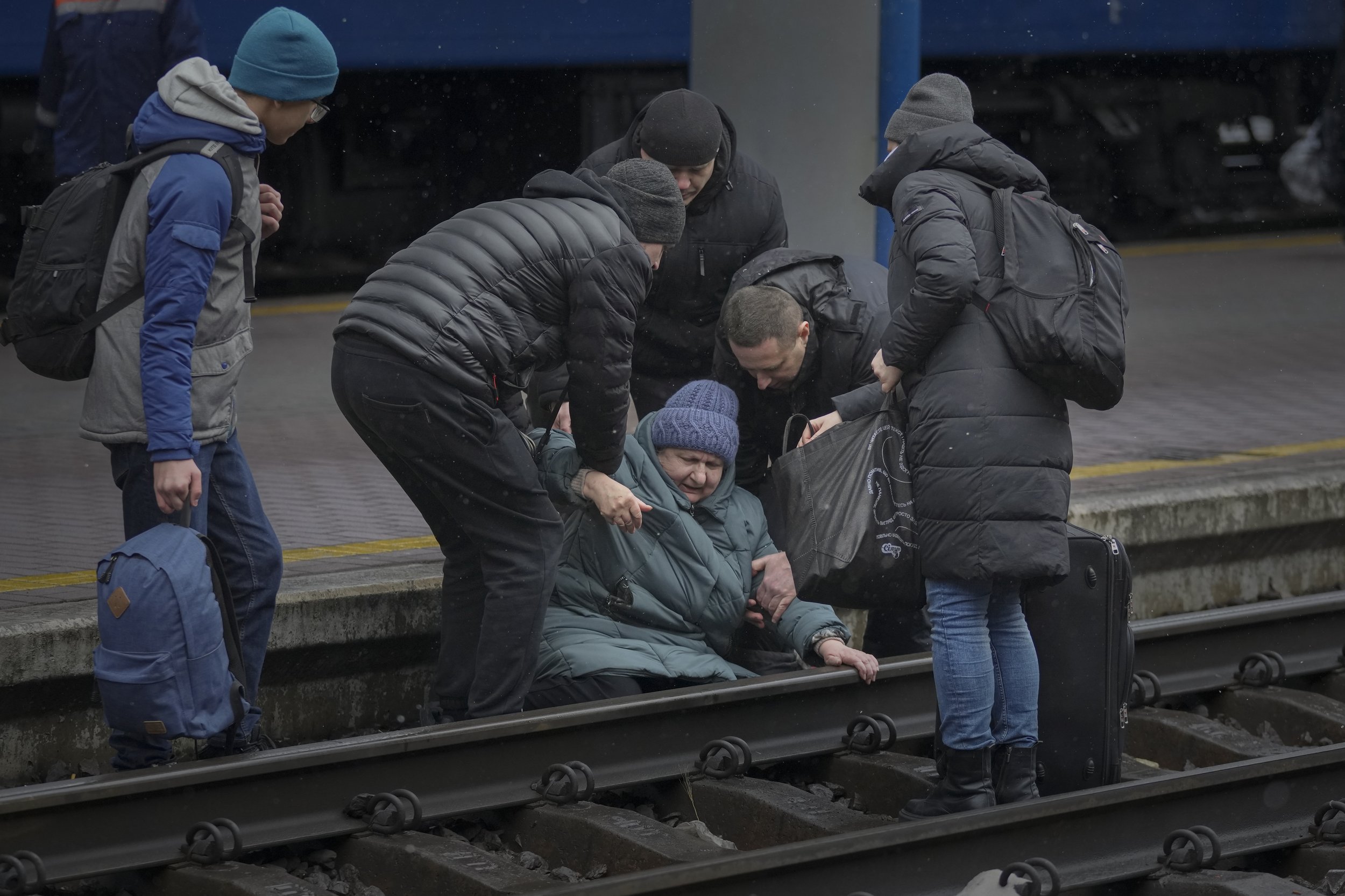  A woman gets help after falling on the tracks trying to reach a Lviv bound train, in Kyiv, Ukraine, Thursday, March 3, 2022.  (AP Photo/Vadim Ghirda) 