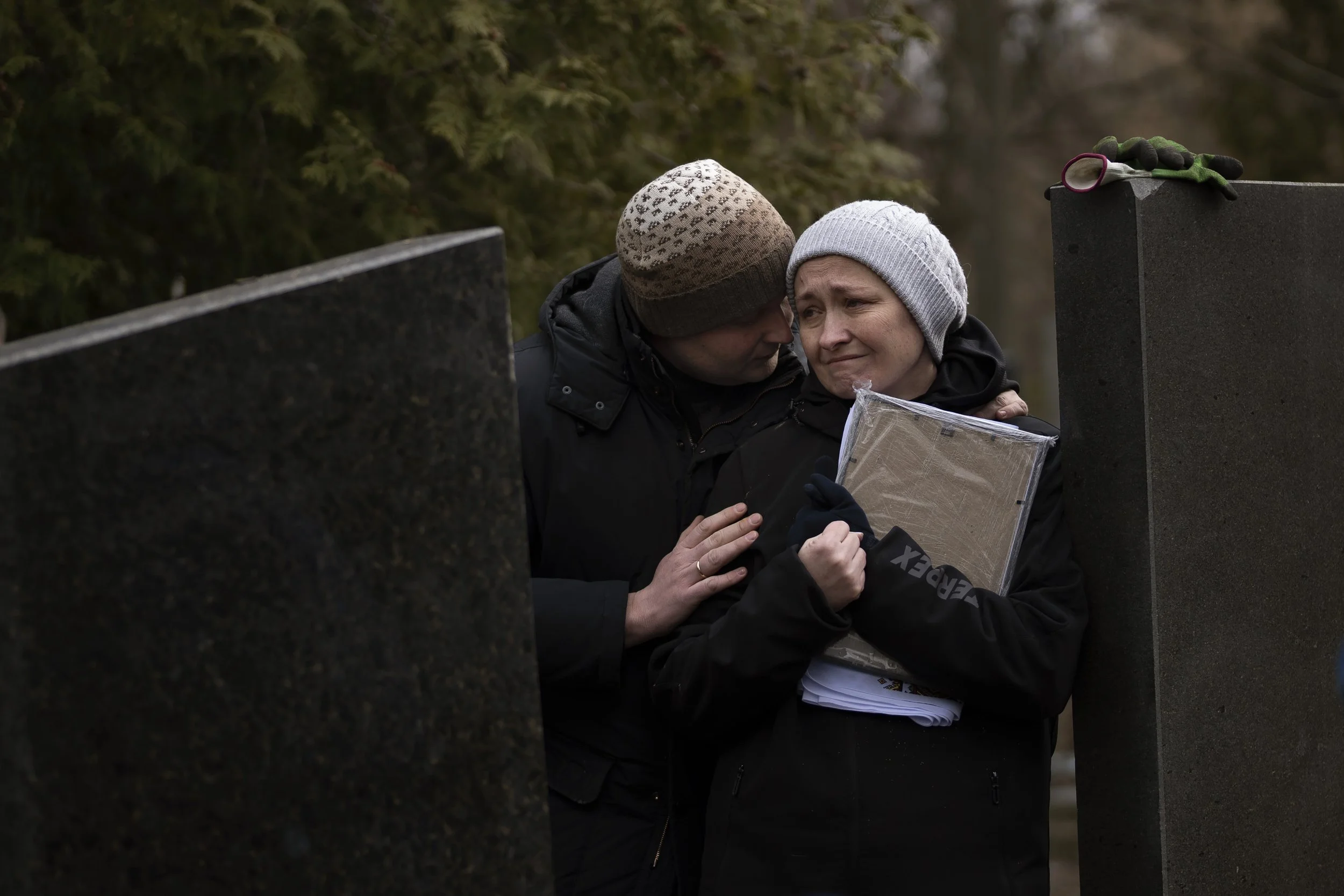 Oksana his hugged by her soon Dmytro during the funeral of her husband Volodymyr Nezhenets, 54, in the city of Kyiv, Ukraine, Friday, March 4, 2022. A small group of reservists are burying their comrade, 54-year-old Volodymyr Nezhenets, who was one