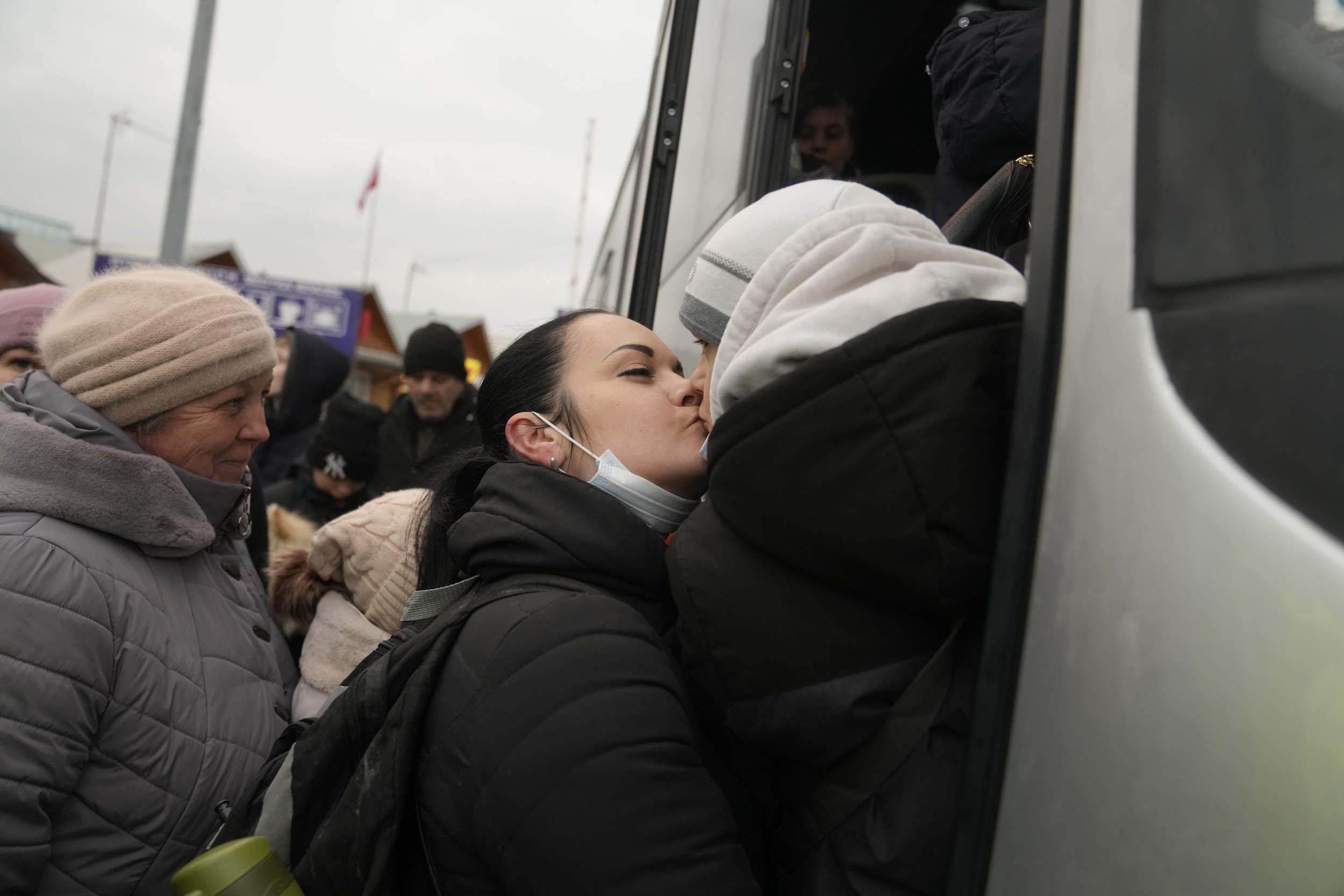 A woman kisses a child as they queue to board a bus after leaving Ukraine at the border crossing in Medyka, Poland, Friday, March 4, 2022. (AP Photo/Markus Schreiber)