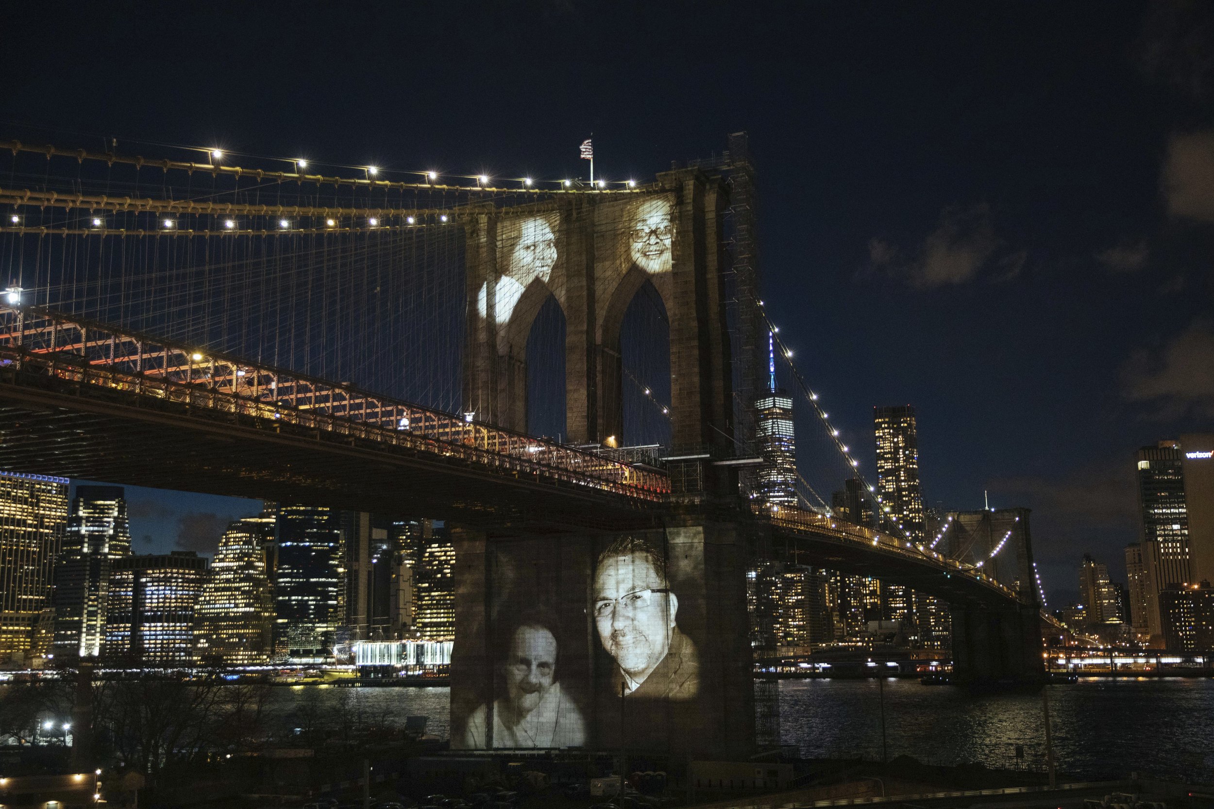  New Yorkers who died during the coronavirus pandemic are projected onto the Brooklyn Bridge during a commemoration ceremony Sunday, March 14, 2021, in Brooklyn, NY. (AP Photo/Kevin Hagen) 