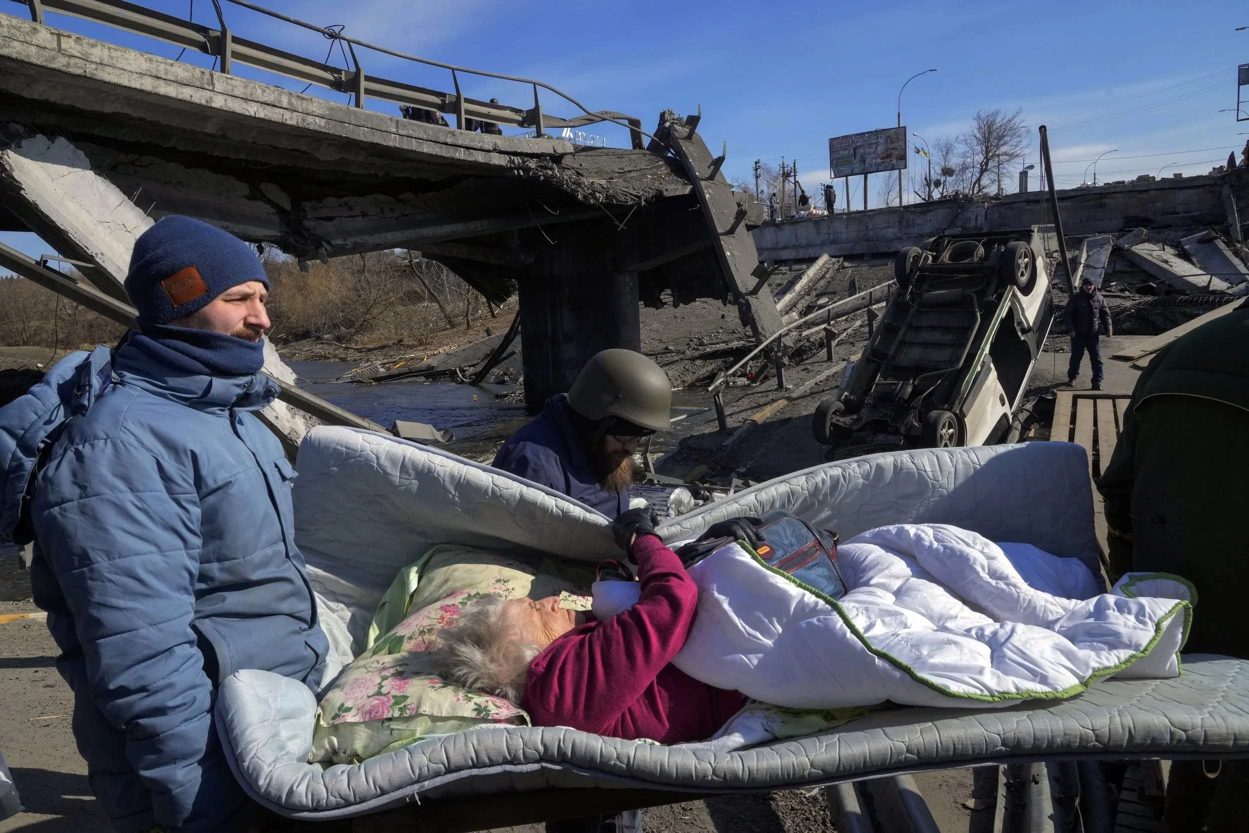  Volunteers pass an improvised path under a destroyed bridge as they evacuate an elderly resident in Irpin, northwest of Kyiv, Friday, March 11, 2022. (AP Photo/Efrem Lukatsky) 
