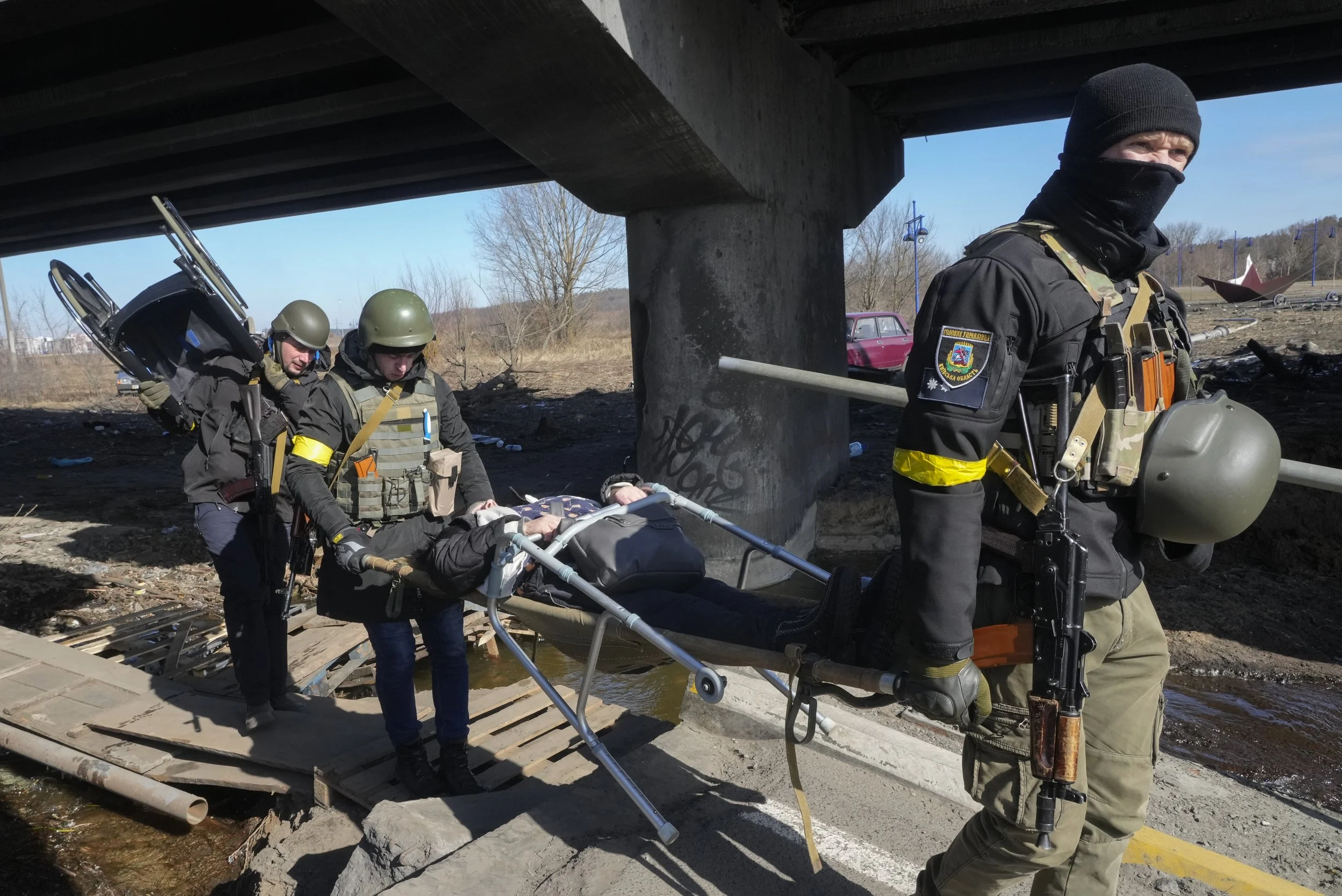  Ukrainians soldiers pass an improvised path under a destroyed bridge as they evacuate an elderly resident in Irpin, northwest of Kyiv, Friday, March 11, 2022. (AP Photo/Efrem Lukatsky) 