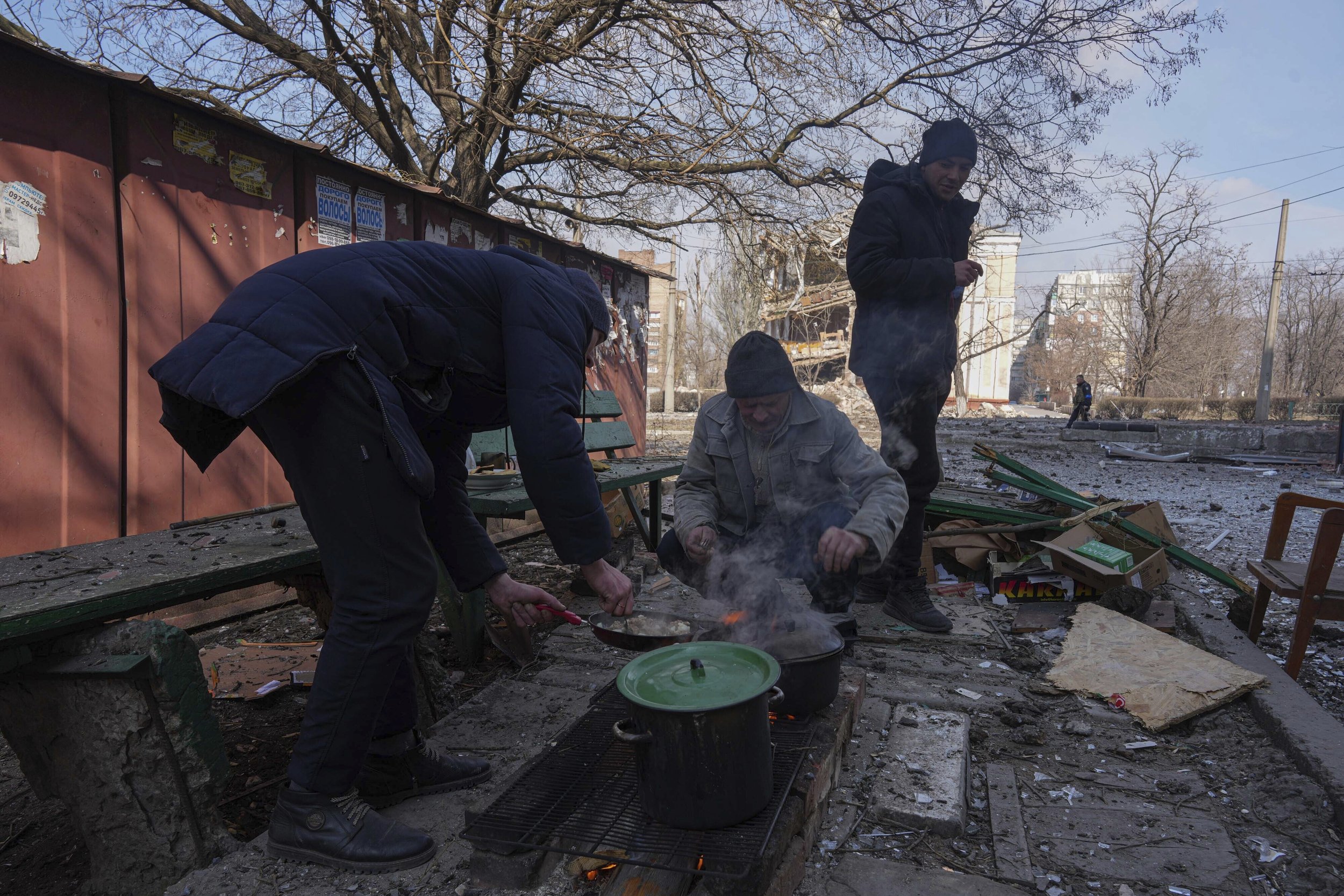  Men cook a meal in a street in Mariupol, Ukraine, Sunday, March 13, 2022. The surrounded southern city of Mariupol, where the war has produced some of the greatest human suffering, remained cut off despite earlier talks on creating aid or evacuation