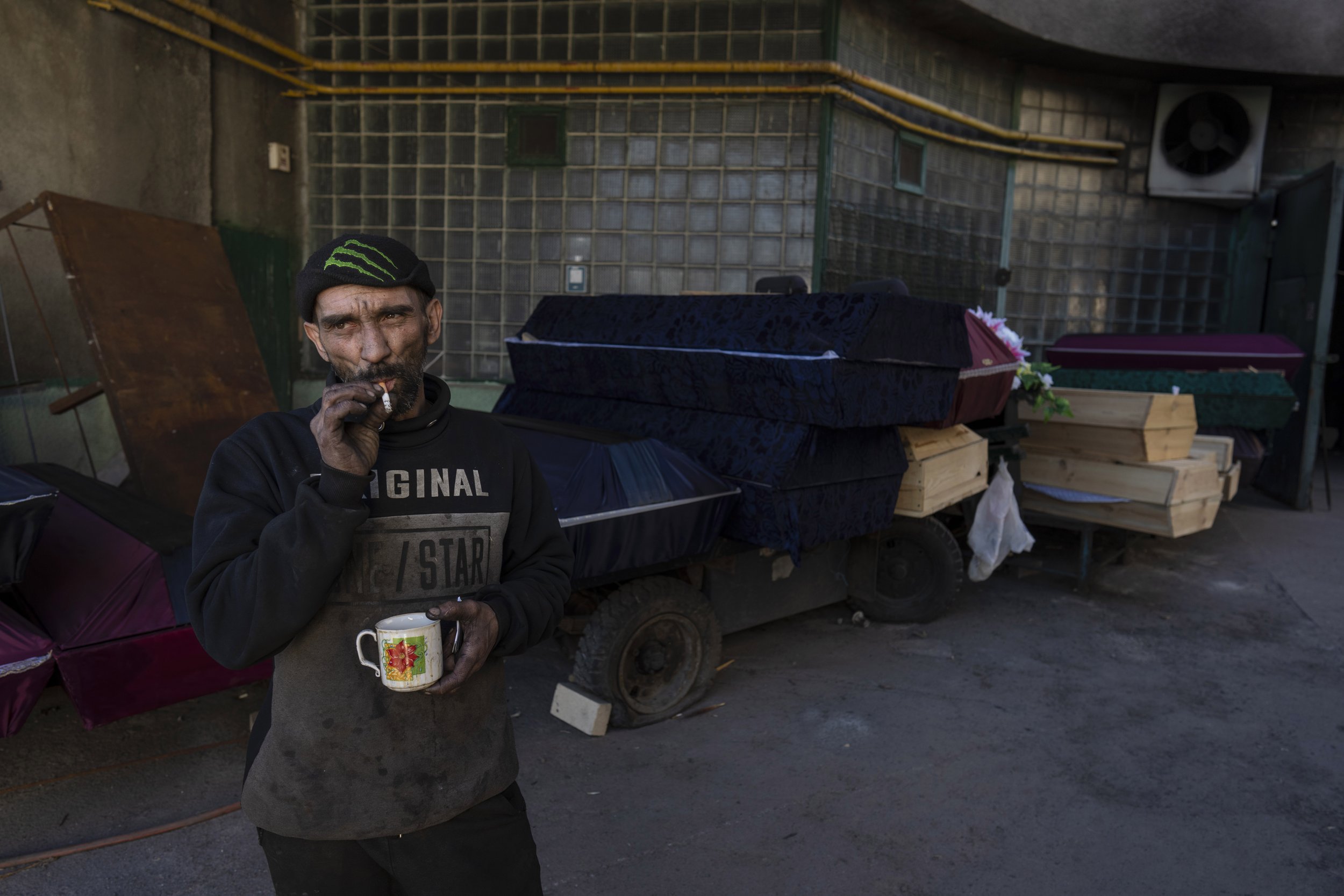  Worker Ruslan Trishchuk, 40, smokes a cigarette while taking a break outside the crematorium of Baikave cemetery in Kyiv, Ukraine, Monday, March 21, 2022. (AP Photo/Rodrigo Abd) 