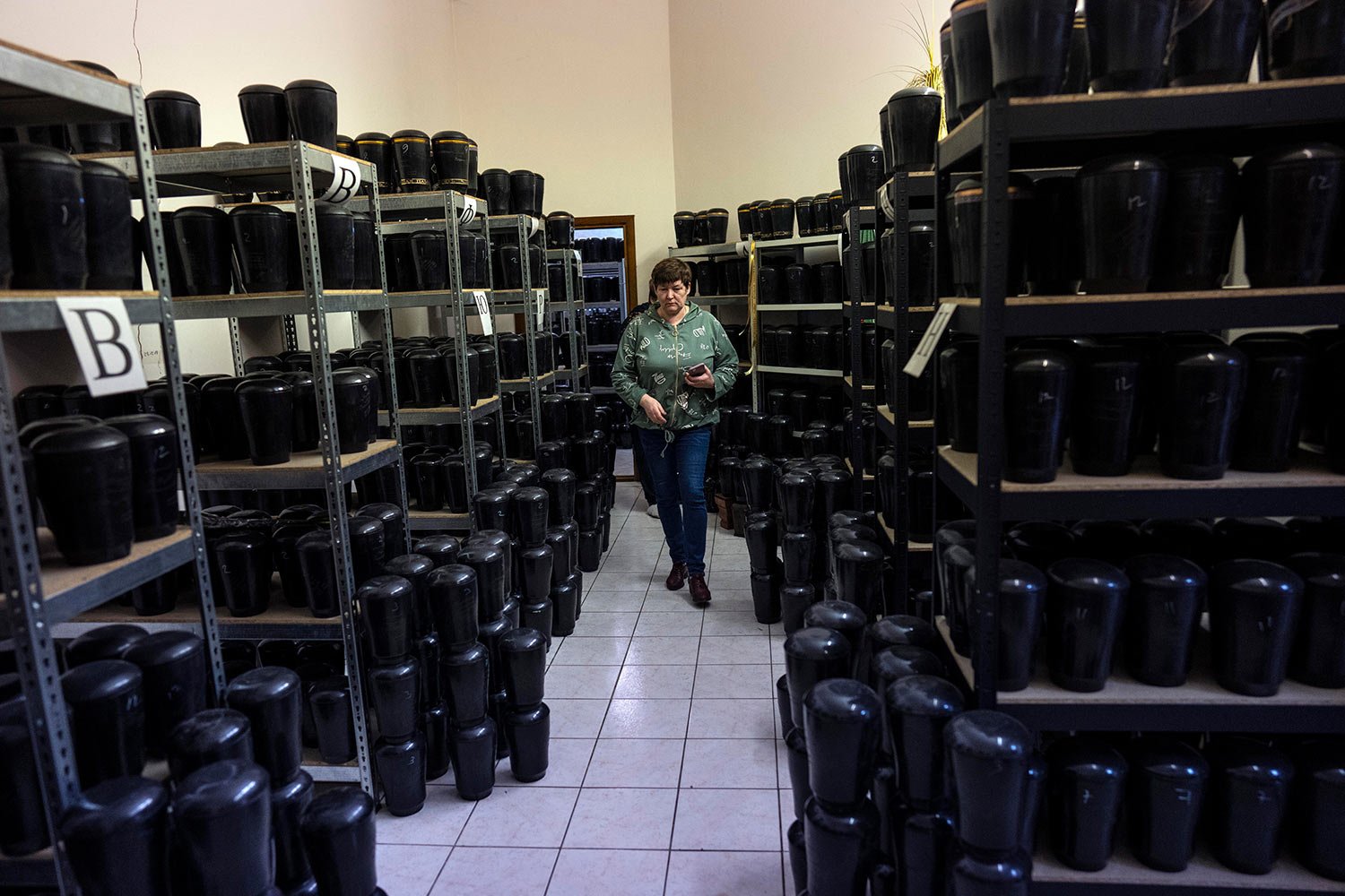  A cemetery worker walks amid marble urns that contains the cremated remains of people inside Baikove's cemetery offices, in Kyiv, Ukraine, Thursday, March 24, 2022. (AP Photo/Rodrigo Abd) 