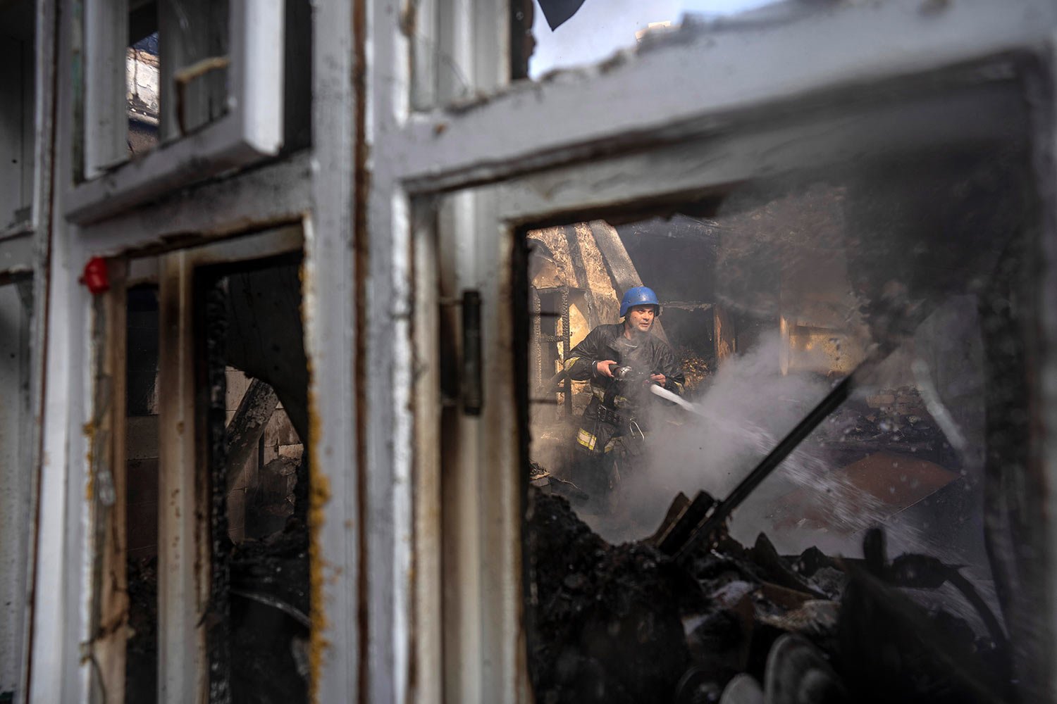  A Ukrainian firefighter tries to extinguish a fire inside a house destroyed by shelling in Kyiv, Ukraine, Wednesday, March 23, 2022. (AP Photo/Rodrigo Abd) 