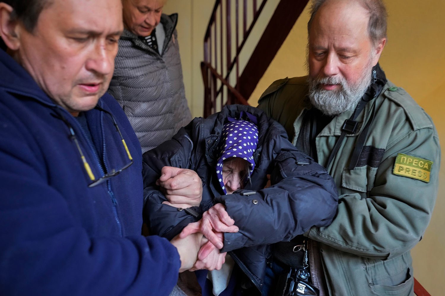  Volunteers help an elderly woman to go downstairs to a bomb shelter in Kharkiv, Ukraine, Friday, March 25, 2022. (AP Photo/Efrem Lukatsky) 