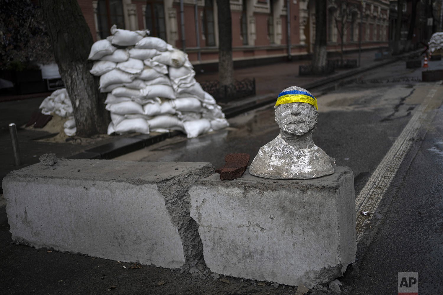  A sculpture adorned with a headband designed with the colors of the Ukraine national flag sits on top of a concrete block at a checkpoint in Kyiv, Ukraine, Saturday, March 26, 2022. With the invasion now in its second month, Russian forces have seem