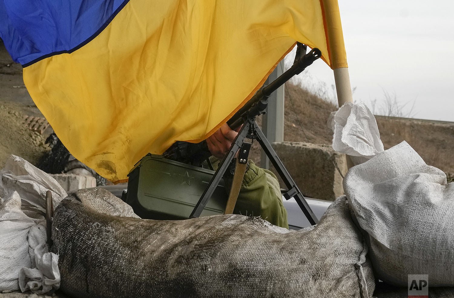  A machine gun emerges from under the Ukrainian flag on a front line position near Kharkiv, Ukraine, Saturday, March 26, 2022. (AP Photo/Efrem Lukatsky) 