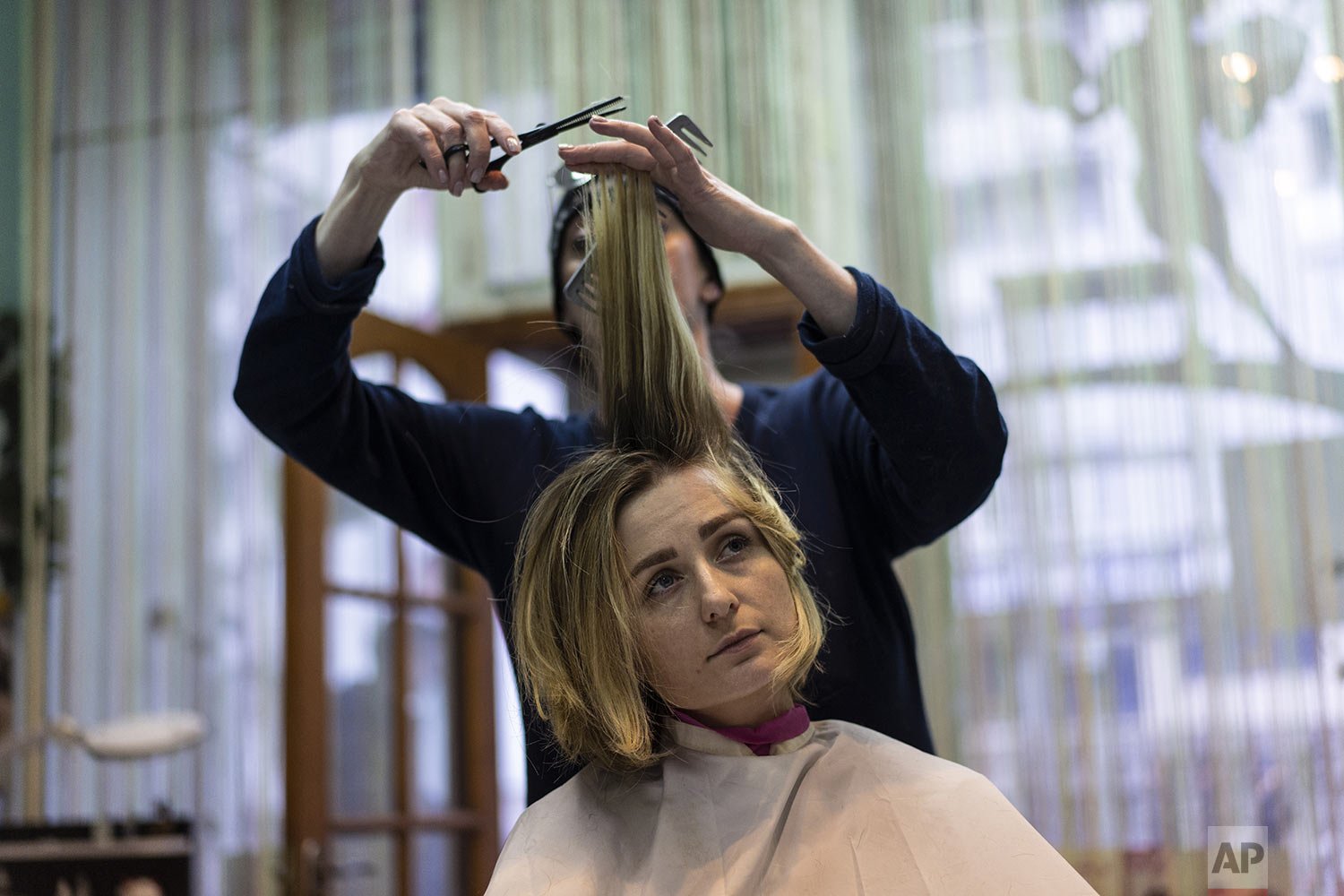  Maria Zolotuhina, 30, relaxes while Elena Kovalenko, 54, cuts her hair in "Figaro" hairdressing in Kyiv, Ukraine, Saturday, March 26, 2022. With the invasion now in its second month, Russian forces have seemingly stalled on many fronts and are even 
