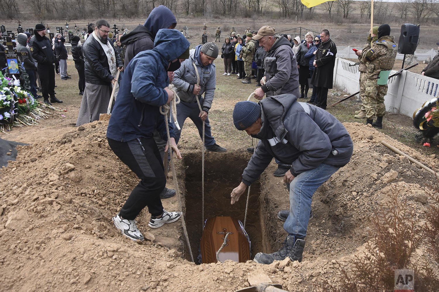  Men lower the coffin of Ukrainian serviceman Oleksiy Lunyov into his gravesite in Yuzhne, Odessa region, Ukraine, Sunday, March 27, 2022. Lunyov was killed during a Russian missile attack in Mykolaiv on March 18. (AP Photo/Max Pshybyshevsky) 