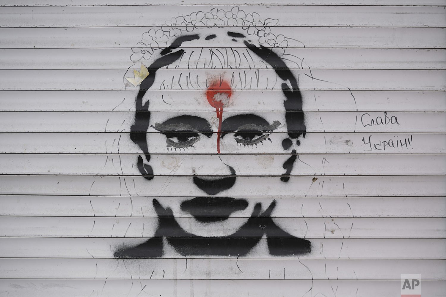  Graffiti depicting Russian President Vladimir Putin and the words “Glory to Ukraine" cover the blinds of a battle-damaged shop in Stoyanka, Ukraine, Sunday, March 27, 2022. (AP Photo/Vadim Ghirda) 