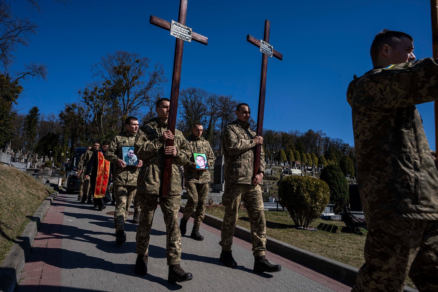  Ukrainian soldiers prepare to bury 32-year-old Senior Lieutenant Pavlo Chernikov, in the photograph at left, and 47-year-old soldier Roman Valkov, during their funeral ceremony, after being killed in action, at the Lychakiv cemetery, in Lviv, wester