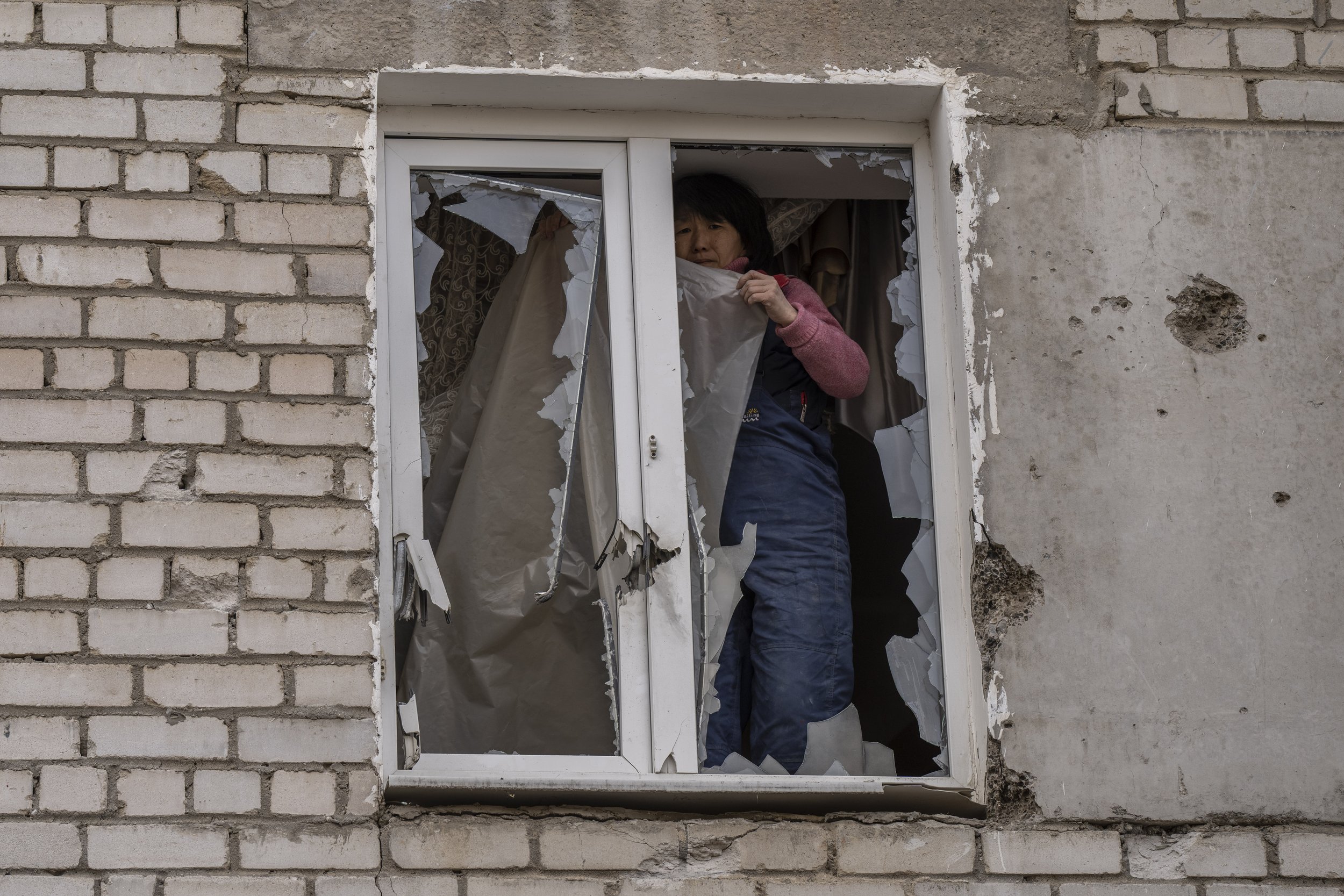 A woman places plastic over her damaged window after a Russian attack on the previous night, in the residential area of Mikolaiv, Ukraine, on Tuesday, March 29, 2022. (AP Photo/Petros Giannakouris) 