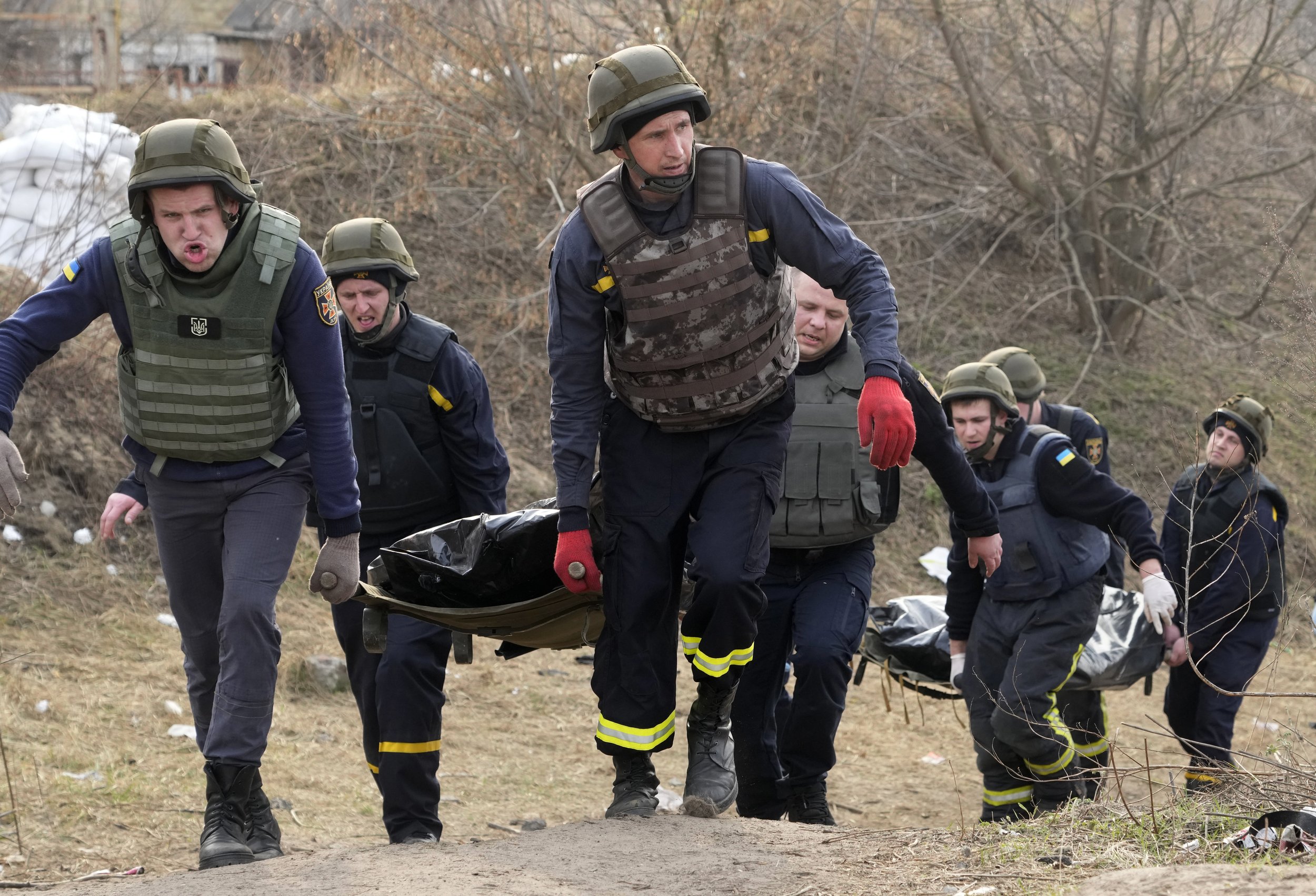  Ukrainian soldiers carry bodies of civilians killed by the Russian forces over the destroyed bridge in Irpin close to Kyiv, Ukraine, Thursday, March 31, 2022. (AP Photo/Efrem Lukatsky) 