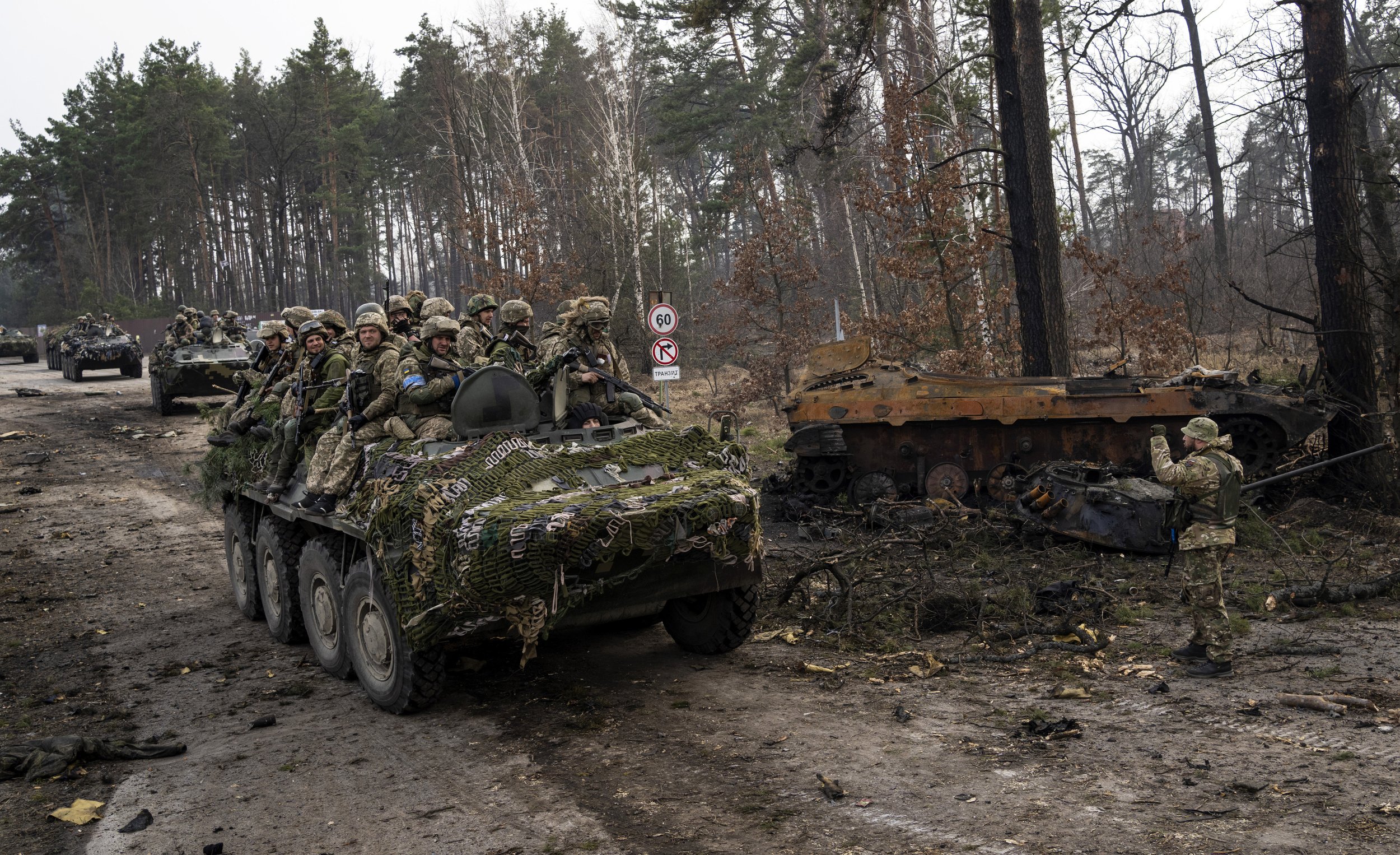  Ukrainian soldiers pass on top of armored vehicles next to a destroyed Russian tank in the outskirts of Kyiv, Ukraine, Thursday, March 31, 2022. (AP Photo/Rodrigo Abd) 