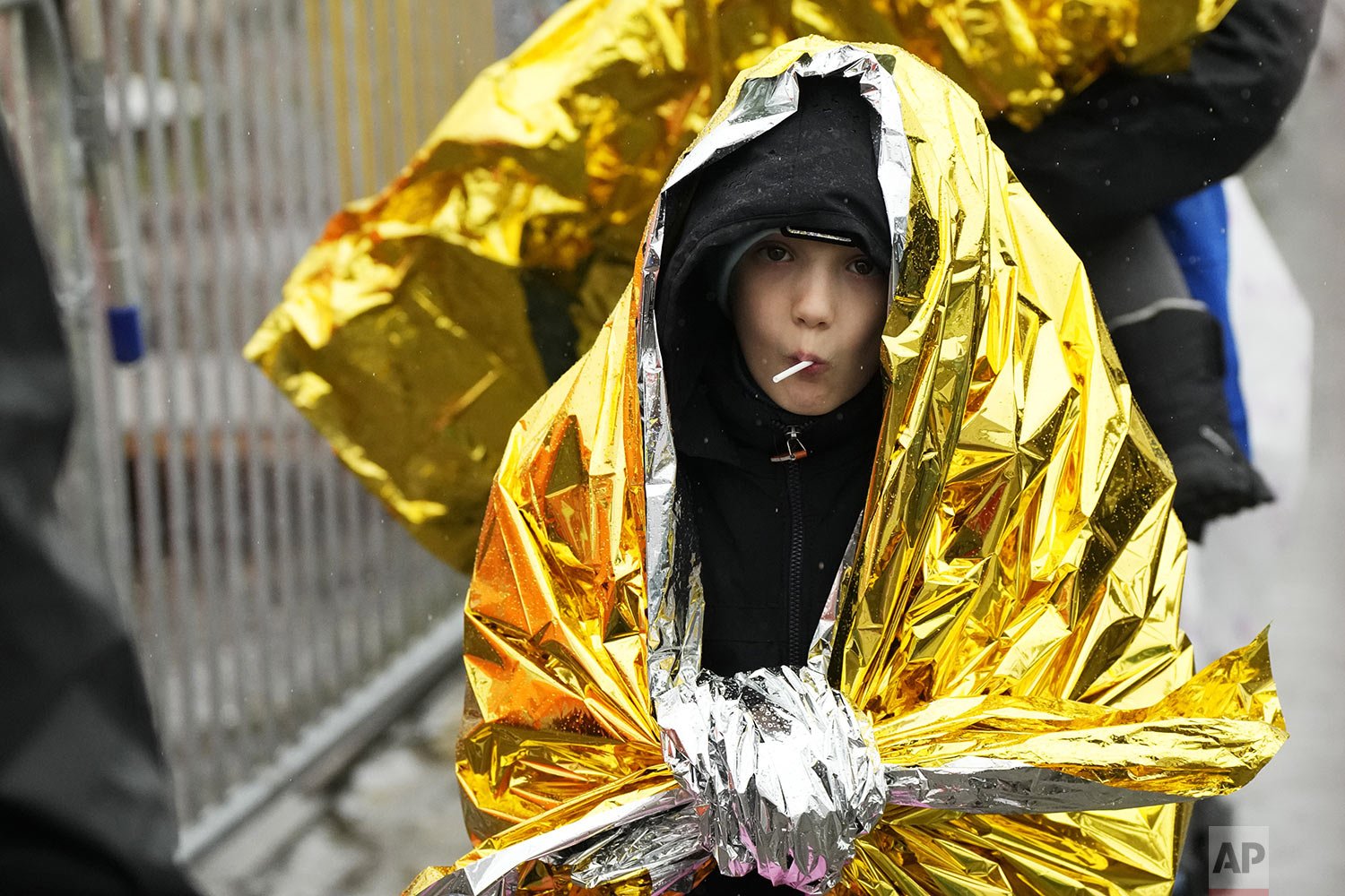  A child wrapped in a rescue emergency blanket, flees the war from neighboring Ukraine crossing the border in Medyka, southeastern Poland, Friday, April 1, 2022. (AP Photo/Sergei Grits) 