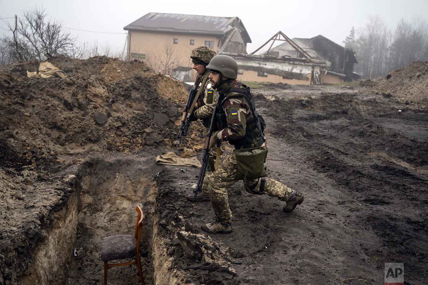  Ukrainian soldiers approach a trench used by Russian soldiers as they retake the area on the outskirts of Kyiv, Ukraine, Friday, April 1, 2022. (AP Photo/Rodrigo Abd) 
