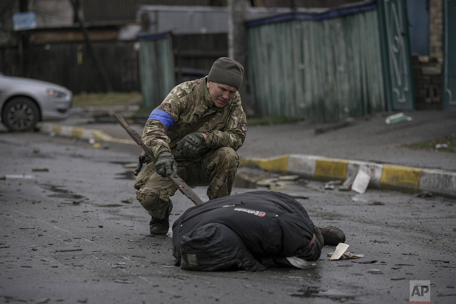  A Ukrainian serviceman uses a piece of wood  to check if the body of a man dressed in civilian clothing is booby-trapped with explosive devices, in the formerly Russian-occupied Kyiv suburb of Bucha, Ukraine, Saturday, April 2, 2022. (AP Photo/Vadim
