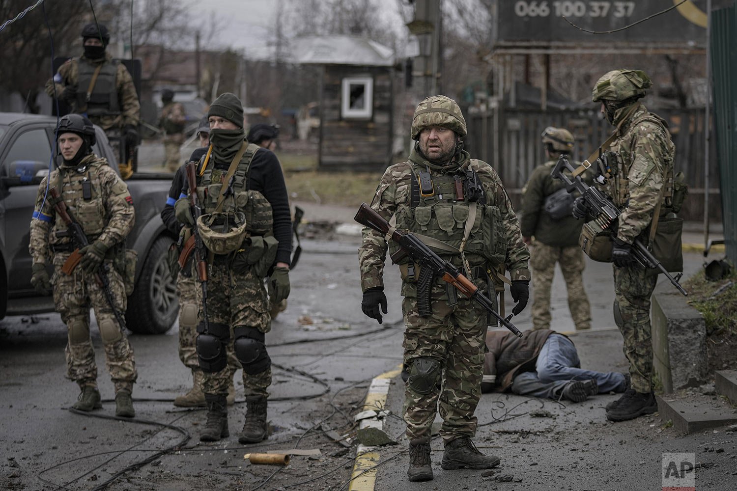  Ukrainian servicemen stand surrounding the body of man dressed in civilian clothing, in the formerly Russian-occupied Kyiv suburb of Bucha, Ukraine, Saturday, April 2, 2022.  (AP Photo/Vadim Ghirda) 