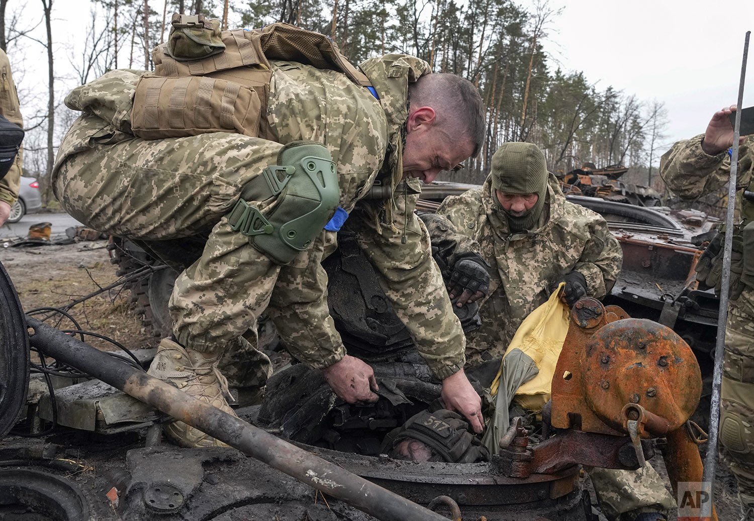  Ukrainian soldiers work to remove the body of a Russian soldier from a destroyed Russian tank, in the village of Dmytrivka close to Kyiv, Ukraine, Saturday, Apr. 2, 2022. (AP Photo/Efrem Lukatsky) 