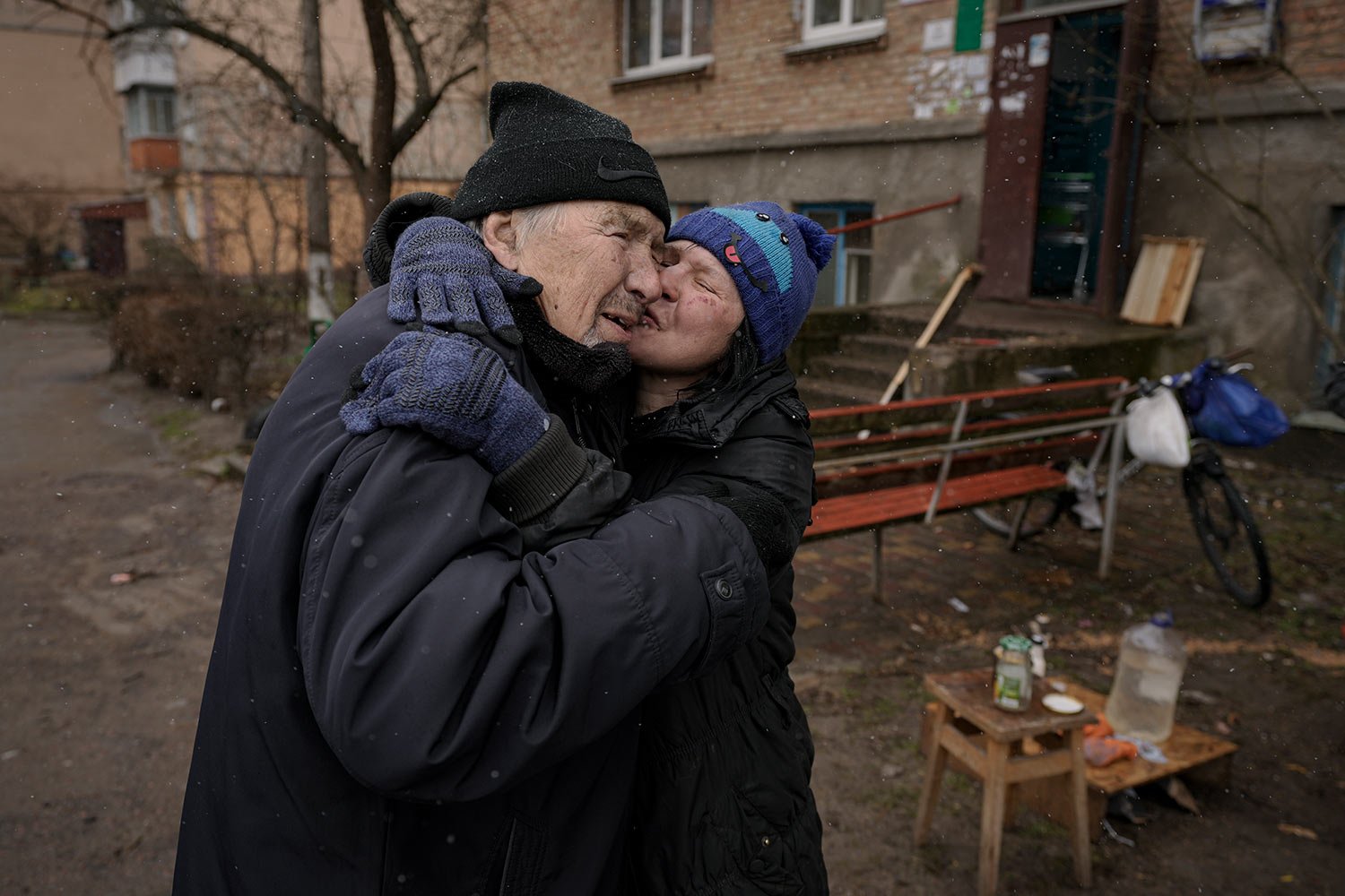  A woman kisses a man while cooking on an open fire outside an apartment building which had no electricity, water or gas since the beginning of the Russian invasion in Bucha, Ukraine, Sunday, April 3, 2022. (AP Photo/Vadim Ghirda) 
