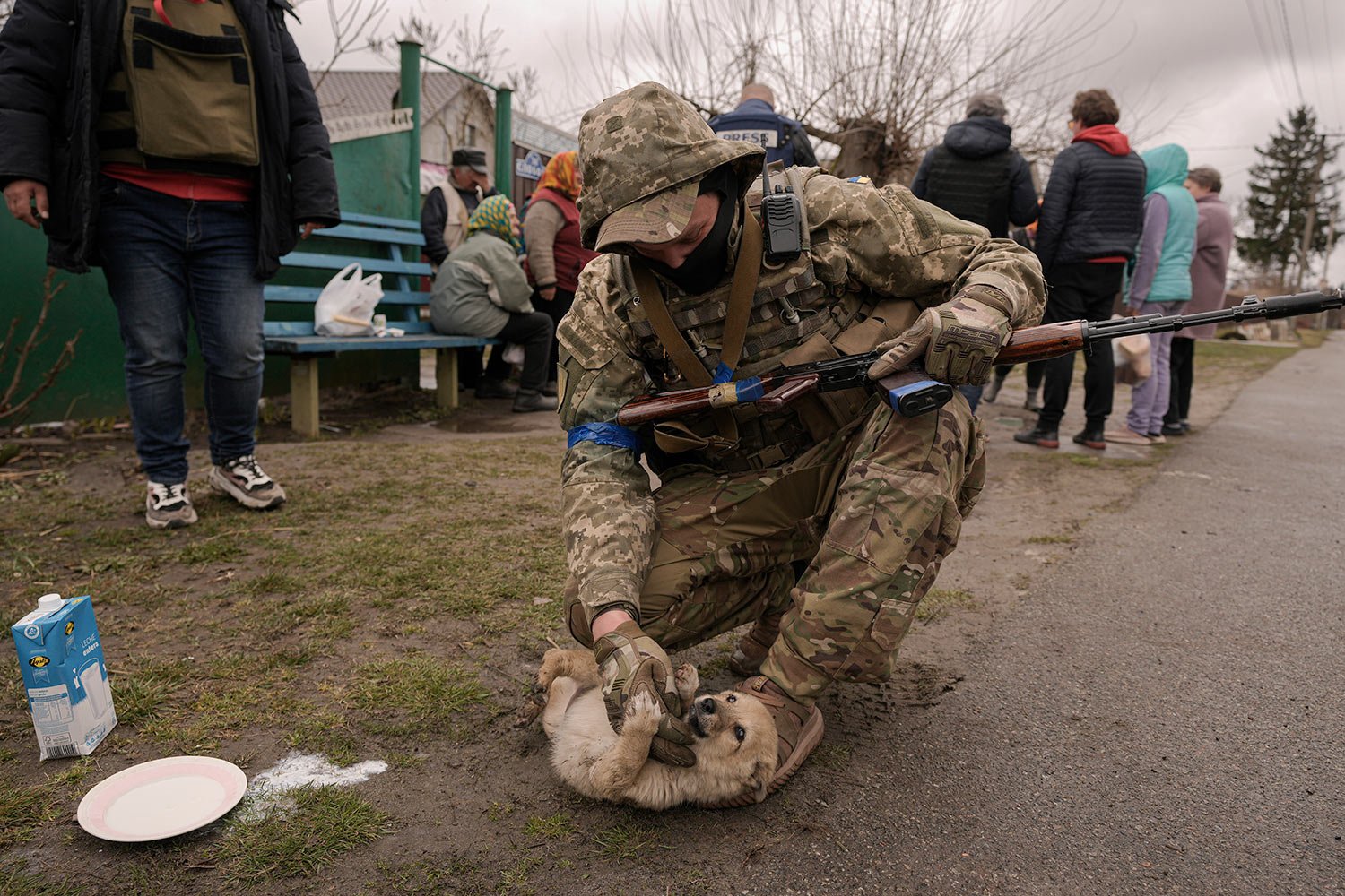  A Ukrainian serviceman tries unsuccessfully to convince a puppy to drink milk as residents wait for distribution of food products in the village of Motyzhyn, Ukraine, which was until recently under the control of the Russian military, Sunday, April 