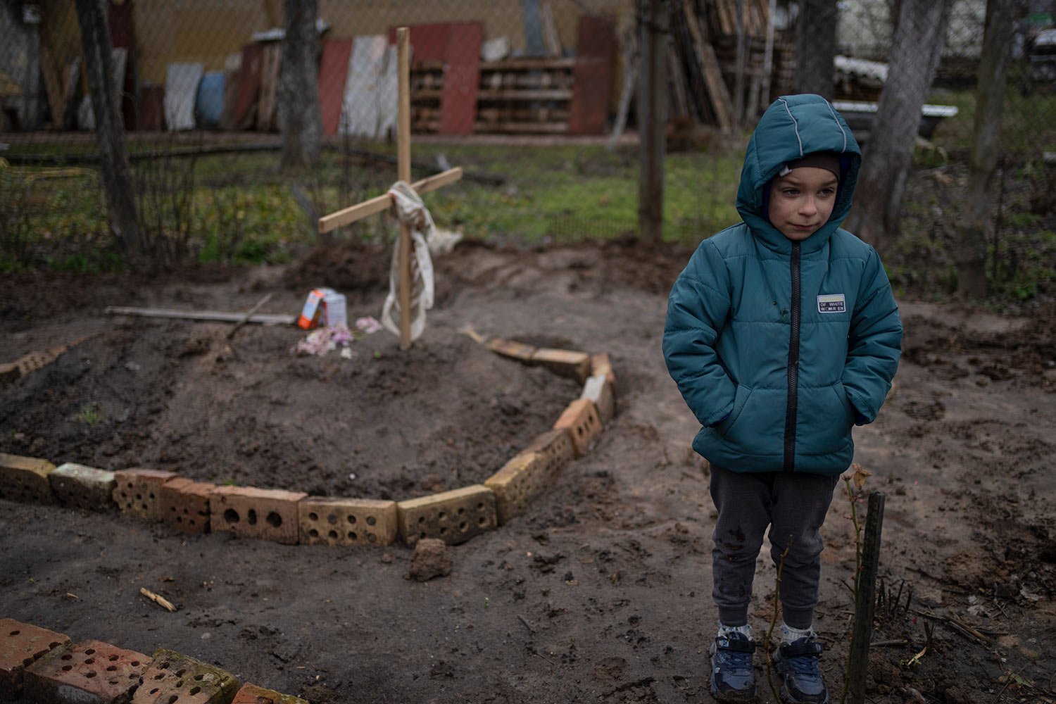  In the courtyard of their house, Vlad Tanyuk, 6, stands near the grave of his mother Ira Tanyuk, who died because of starvation and stress due to the war, on the outskirts of Kyiv, Ukraine, Monday, April 4, 2022. (AP Photo/Rodrigo Abd) 