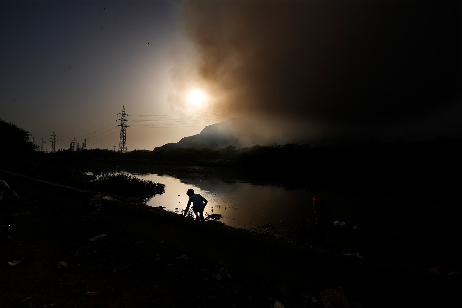  A child plays near a drainage as a massive fire engulfs the Ghazipur garbage dump in New Delhi, India, Monday, March 28, 2022. (AP Photo/Manish Swarup) 