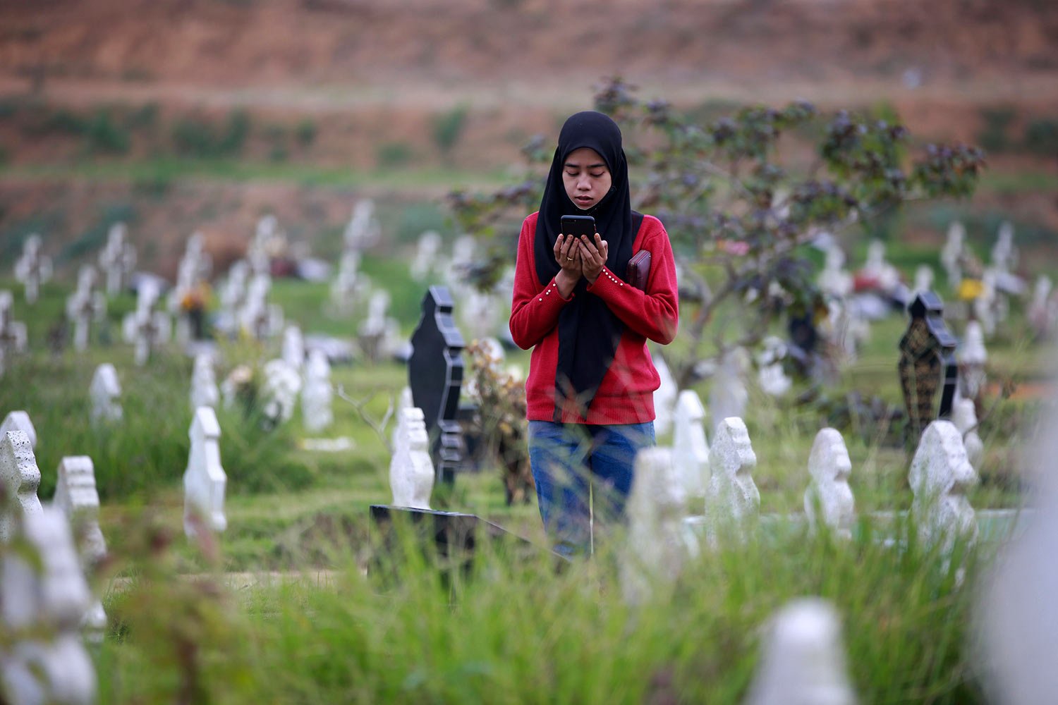  A Muslim woman prays at the grave of a relative at a cemetery reserved for those who died of COVID-19, in Medan, North Sumatra, Indonesia, Thursday, March 31, 2022. (AP Photo/Binsar Bakkara) 