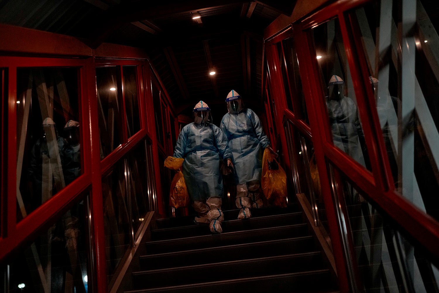  Health workers wearing protective suits carry COVID-19 test samples as they walk through a passageway at a hotel inside the Olympic bubble during the 2022 Winter Paralympics, Monday, March 7, 2022, in the Yanqing district of Beijing.  (AP Photo/Andy