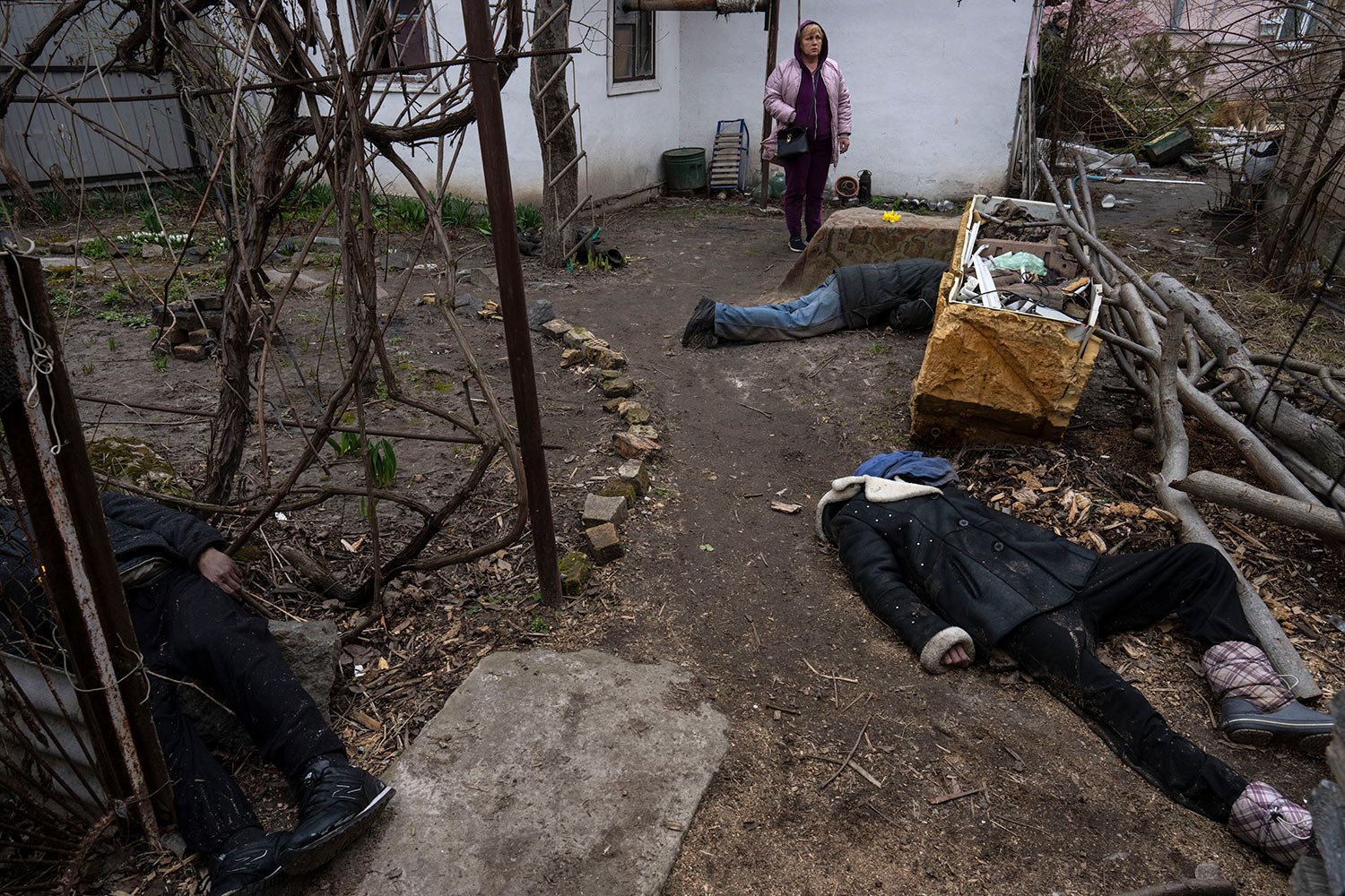  A woman stands next to three people killed in the courtyard of a house in Bucha, on the outskirts of Kyiv, Ukraine, Tuesday, April 5, 2022. (AP Photo/Rodrigo Abd) 