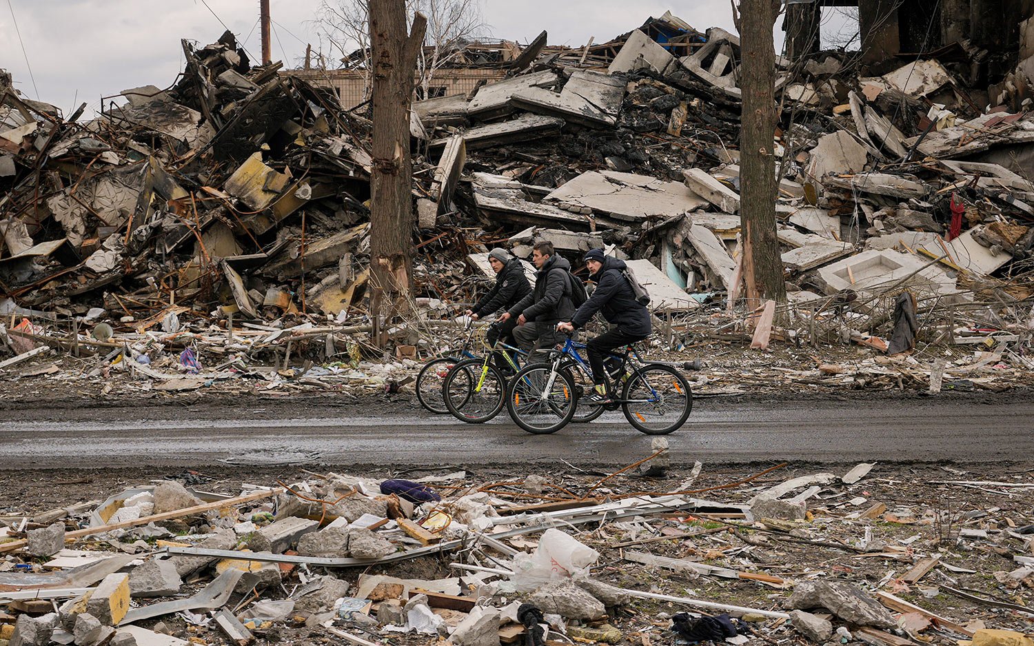  Men ride bicycles by a destroyed apartment building in Borodyanka, Ukraine, Wednesday, April 6, 2022. (AP Photo/Vadim Ghirda) 