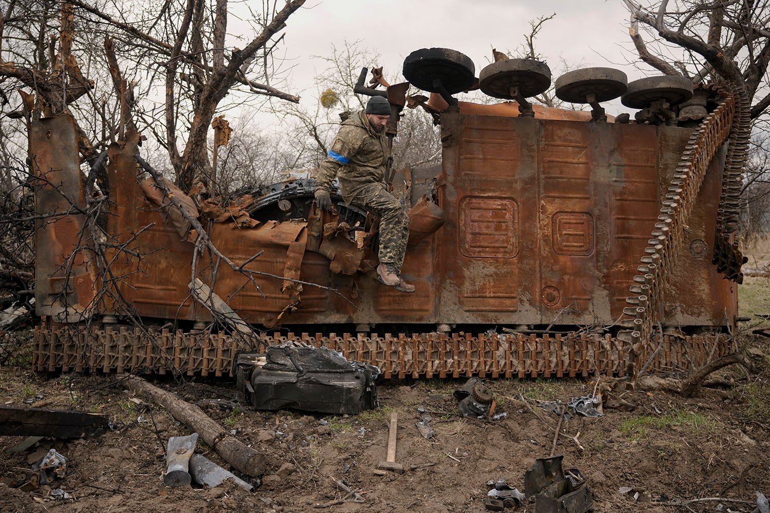  A Ukrainian serviceman jumps from a destroyed Russian fighting vehicle after collecting parts and ammunition in the village of Andriivka, Ukraine, heavily affected by fighting between Russian and Ukrainian forces, Wednesday, April 6, 2022. (AP Photo