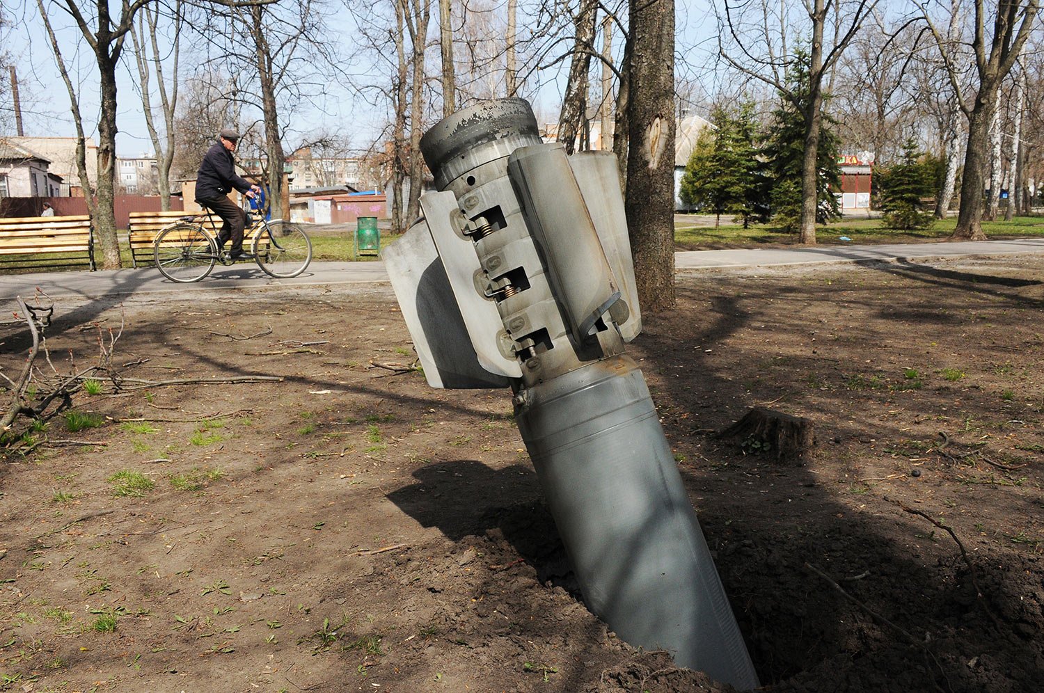  A man rides a bicycle as a tail of a missile sticks out in the city of Chuhuiv, Kharkiv region, Ukraine, Friday, April 8, 2022. (AP Photo/Andrew Marienko) 