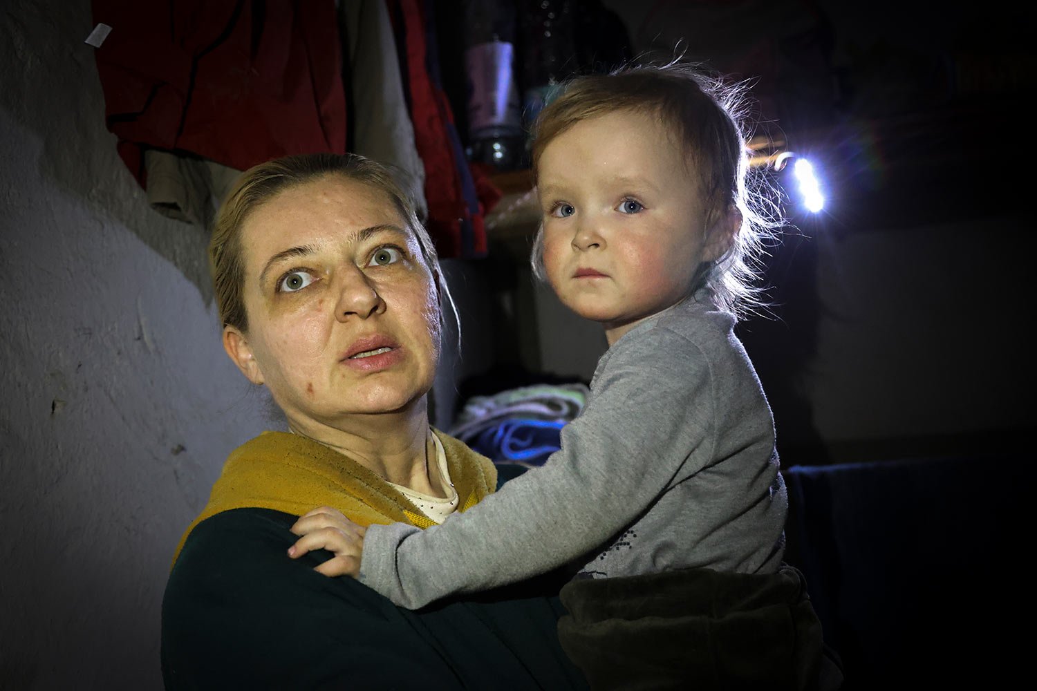  A woman holds her child as she speaks to a photographer in the basement of a building damaged during a fighting used as a bomb shelter in Mariupol, on the territory which is now under the Government of the Donetsk People's Republic control, eastern 