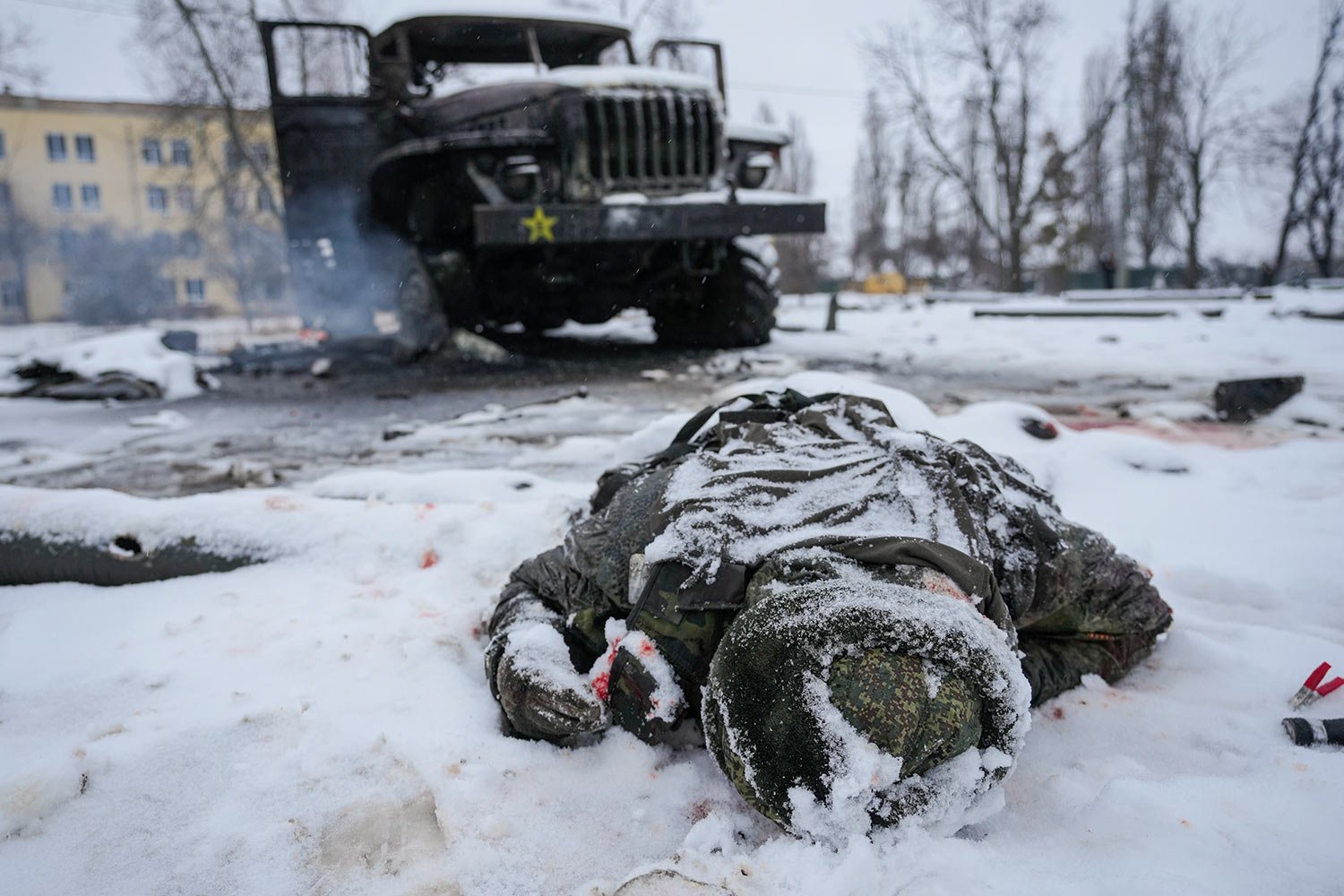  The body of a serviceman is coated in snow next to a destroyed Russian military multiple rocket launcher vehicle on the outskirts of Kharkiv, Ukraine, Friday, Feb. 25, 2022. (AP Photo/Vadim Ghirda) 