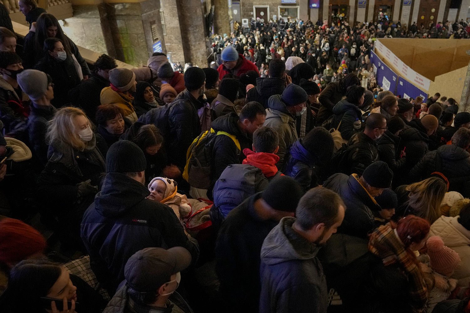  A man carries a baby as people struggle on stairways after a last minute change of the departure platform for a Lviv bound train in Kyiv, Ukraine, Monday, Feb. 28, 2022. (AP Photo/Vadim Ghirda) 