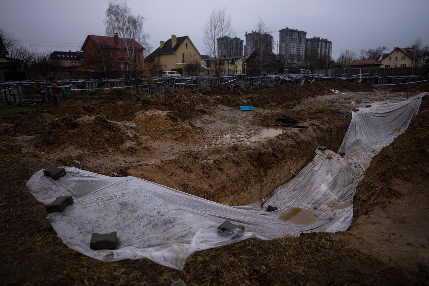  A plastic sheet covers a mass grave with civilians killed during the war against Russia in Bucha, in the outskirts of Kyiv, Ukraine, Sunday, April 10, 2022. (AP Photo/Rodrigo Abd) 